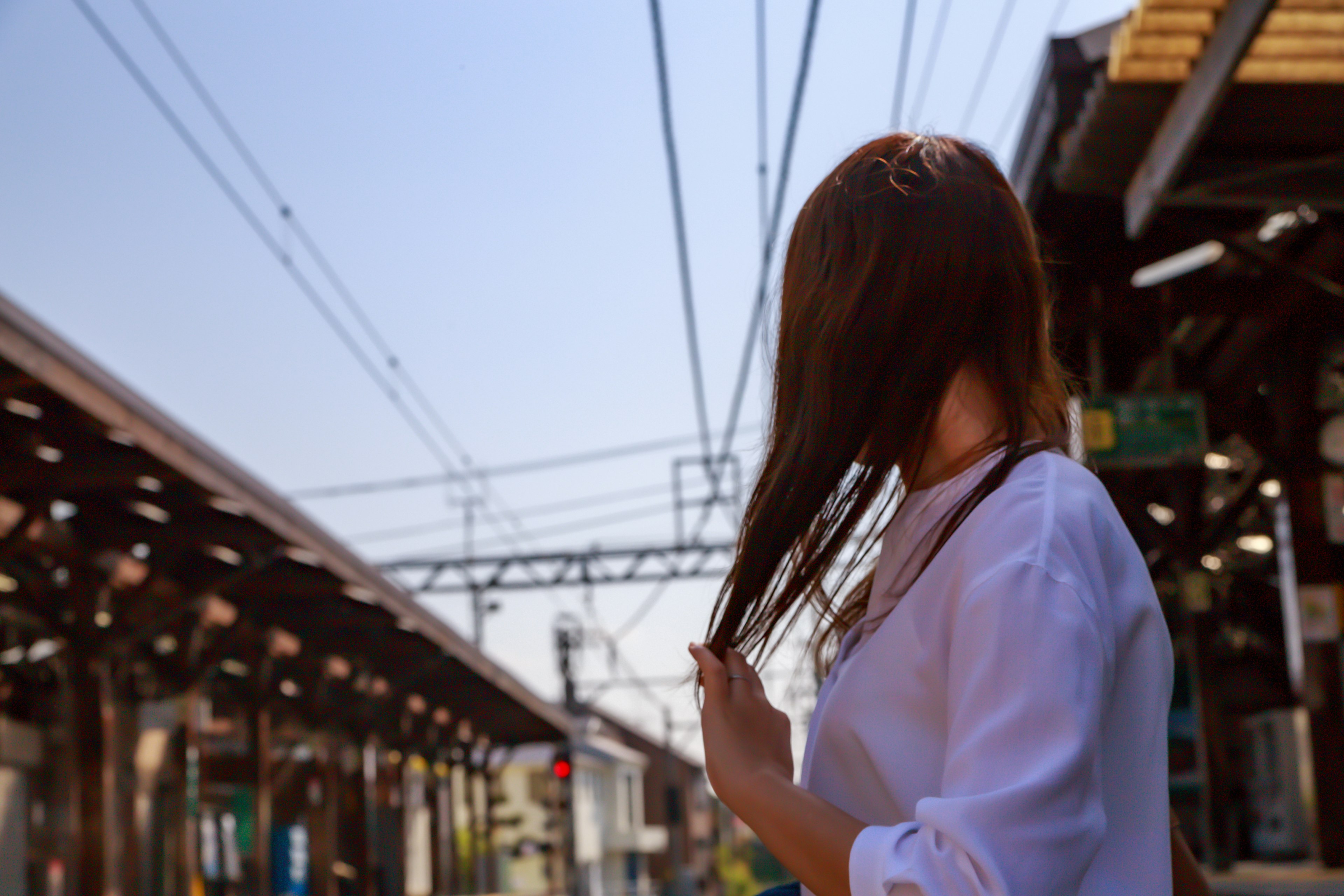 Une femme se tient sur un quai de train en touchant ses cheveux