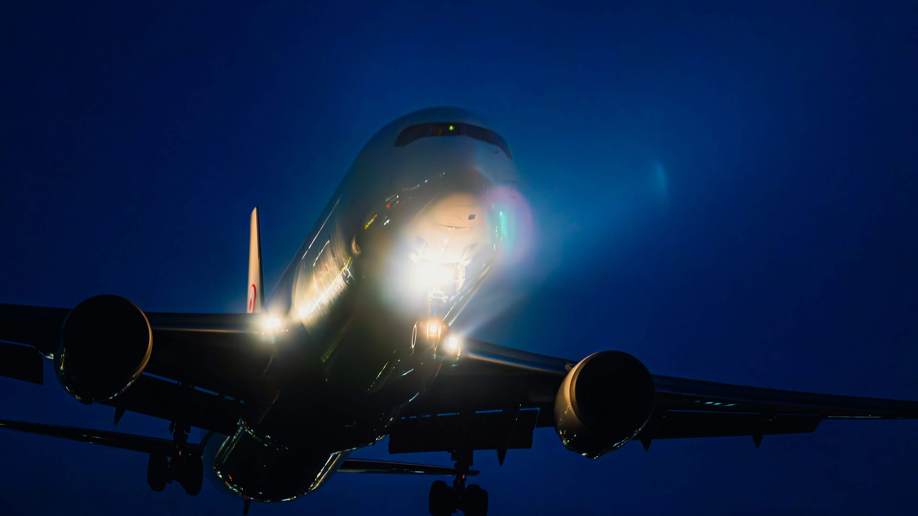 Aerial view of an aircraft approaching at night with bright landing lights