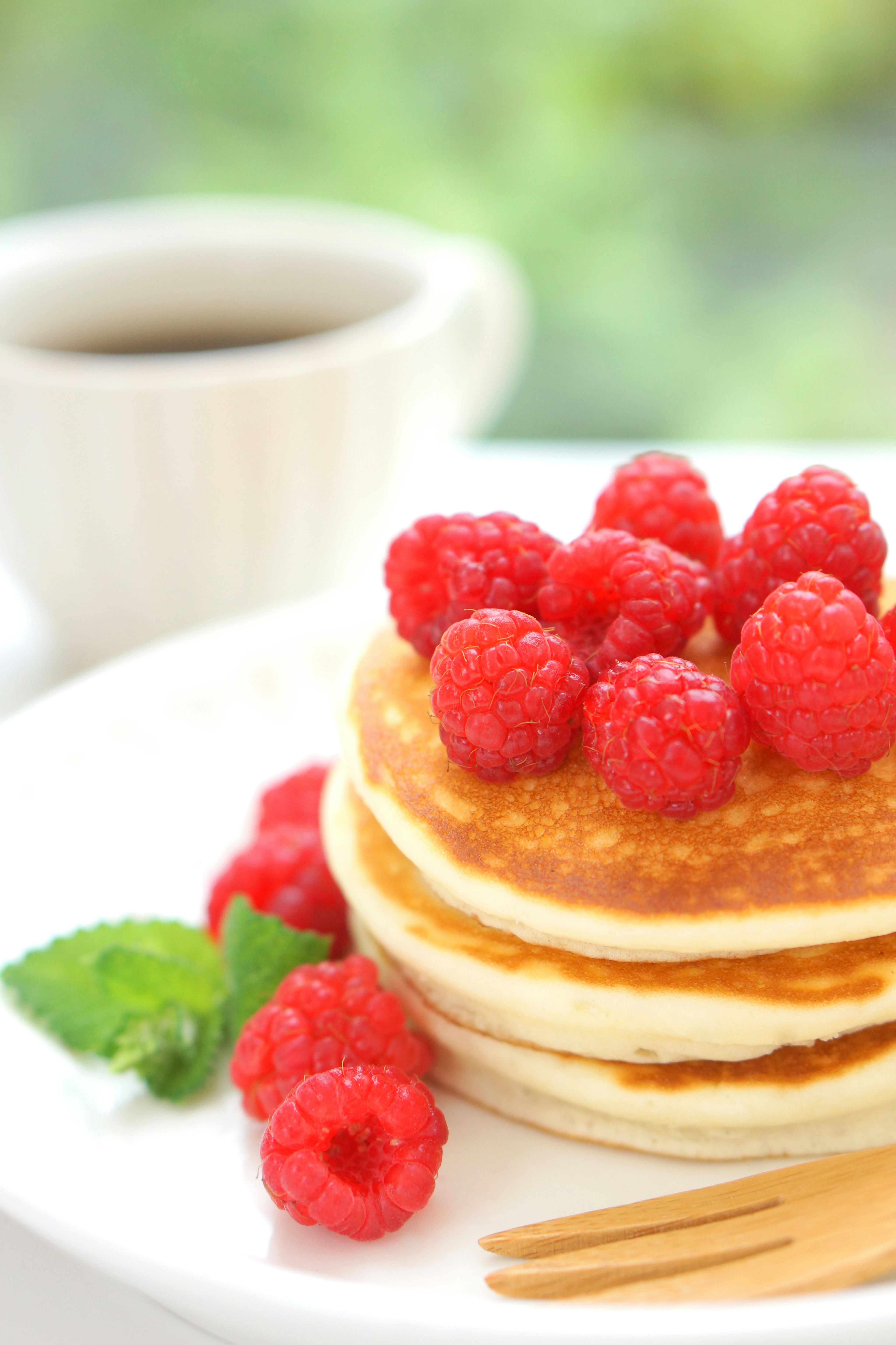 Panqueques cubiertos con frambuesas y una taza de café