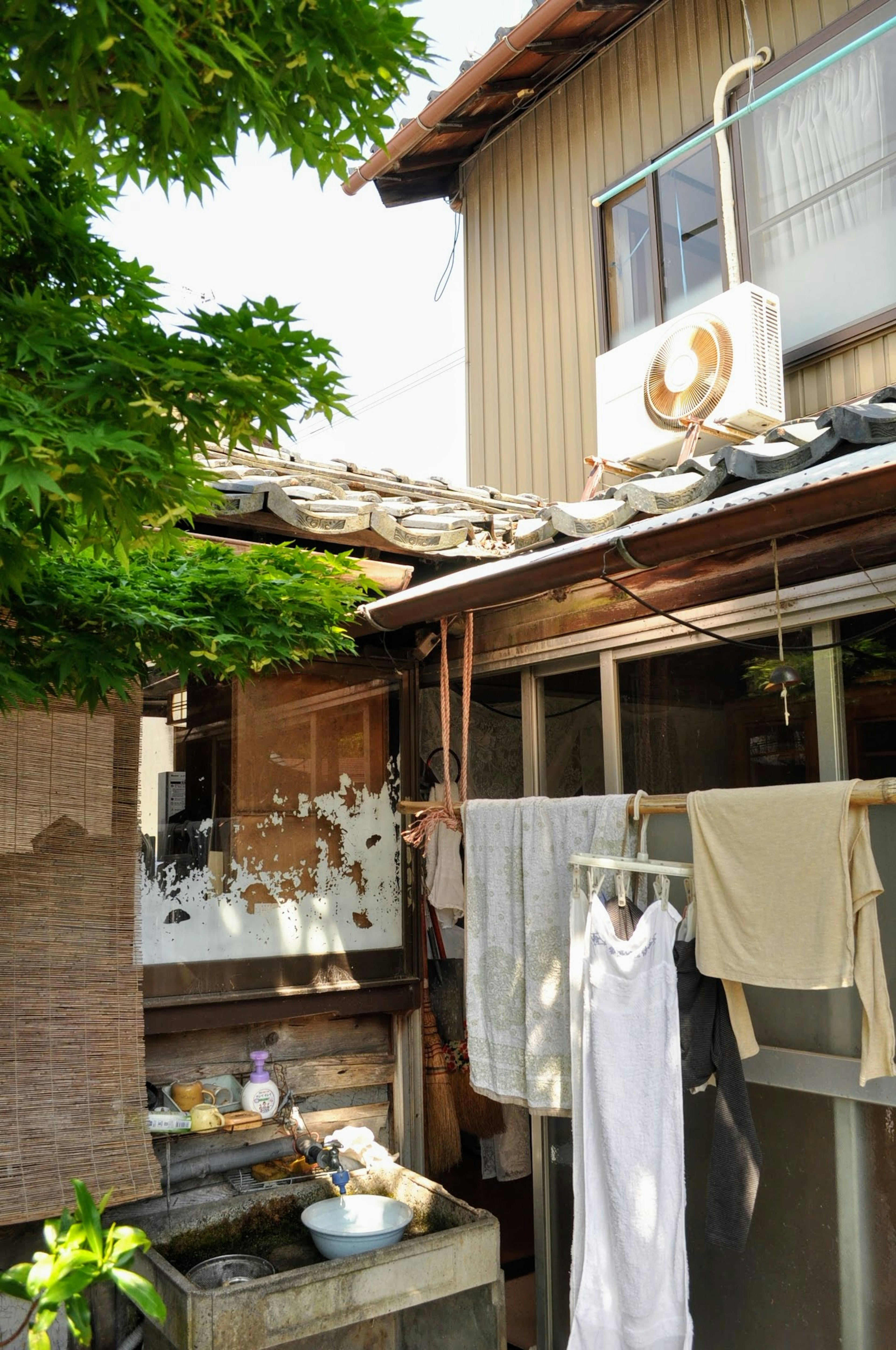 Jardin d'une vieille maison japonaise avec du linge suspendu et des arbres verts