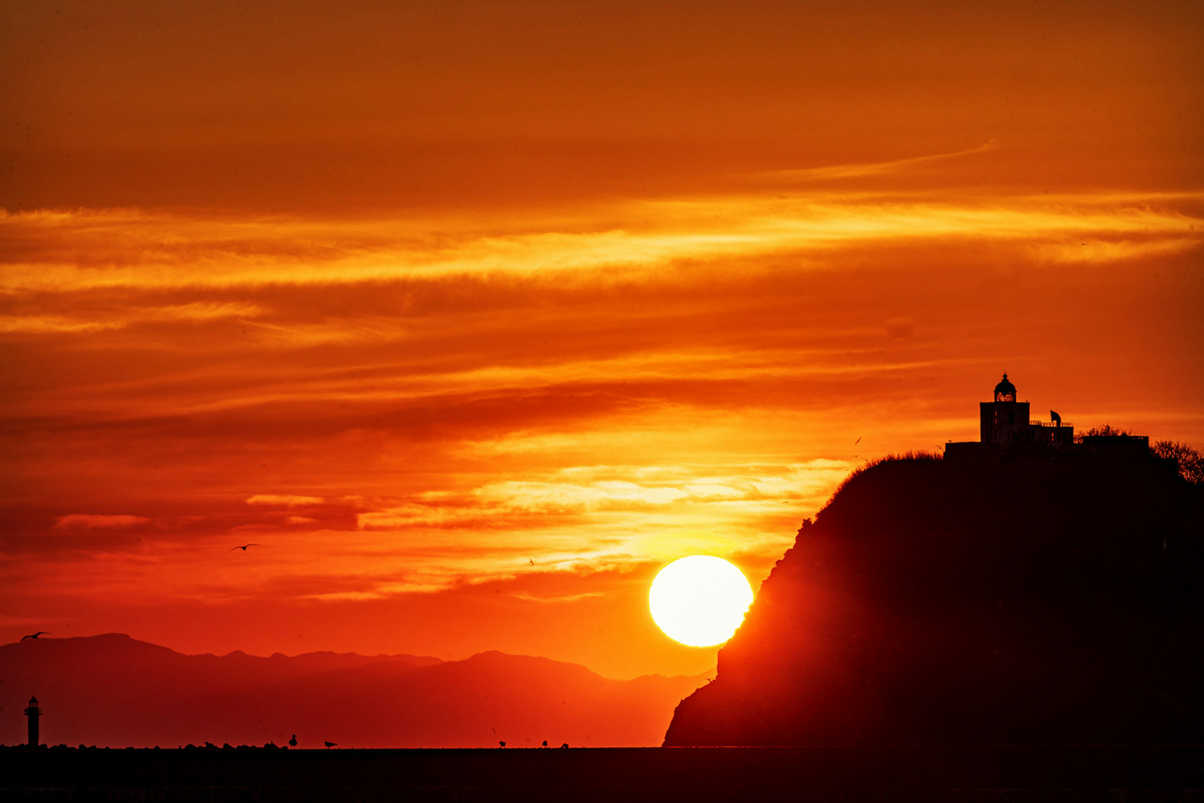 Sunset over a mountain with a lighthouse