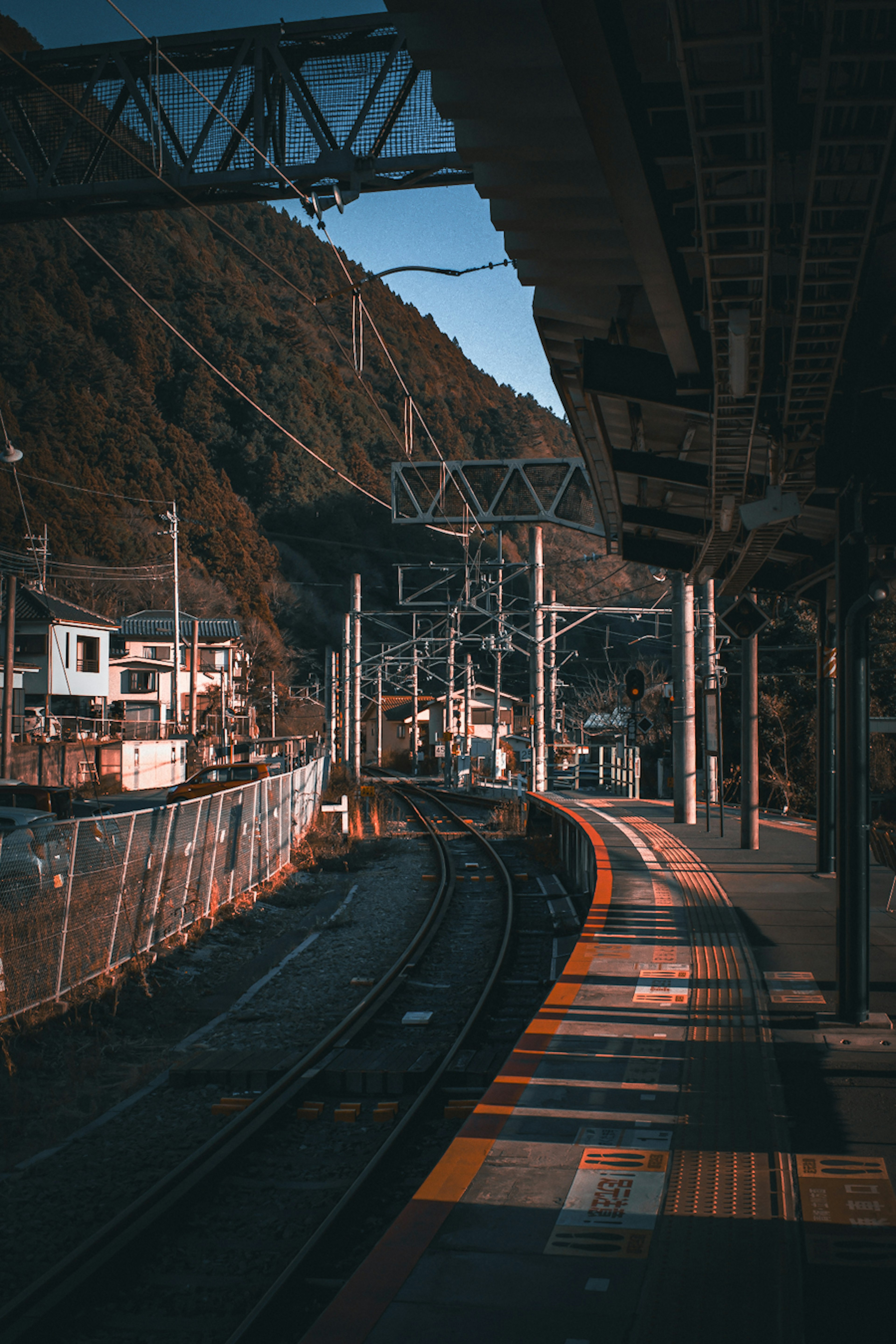 ชานชาลาสถานีรถไฟพร้อมภูเขารอบข้างและรางรถไฟ