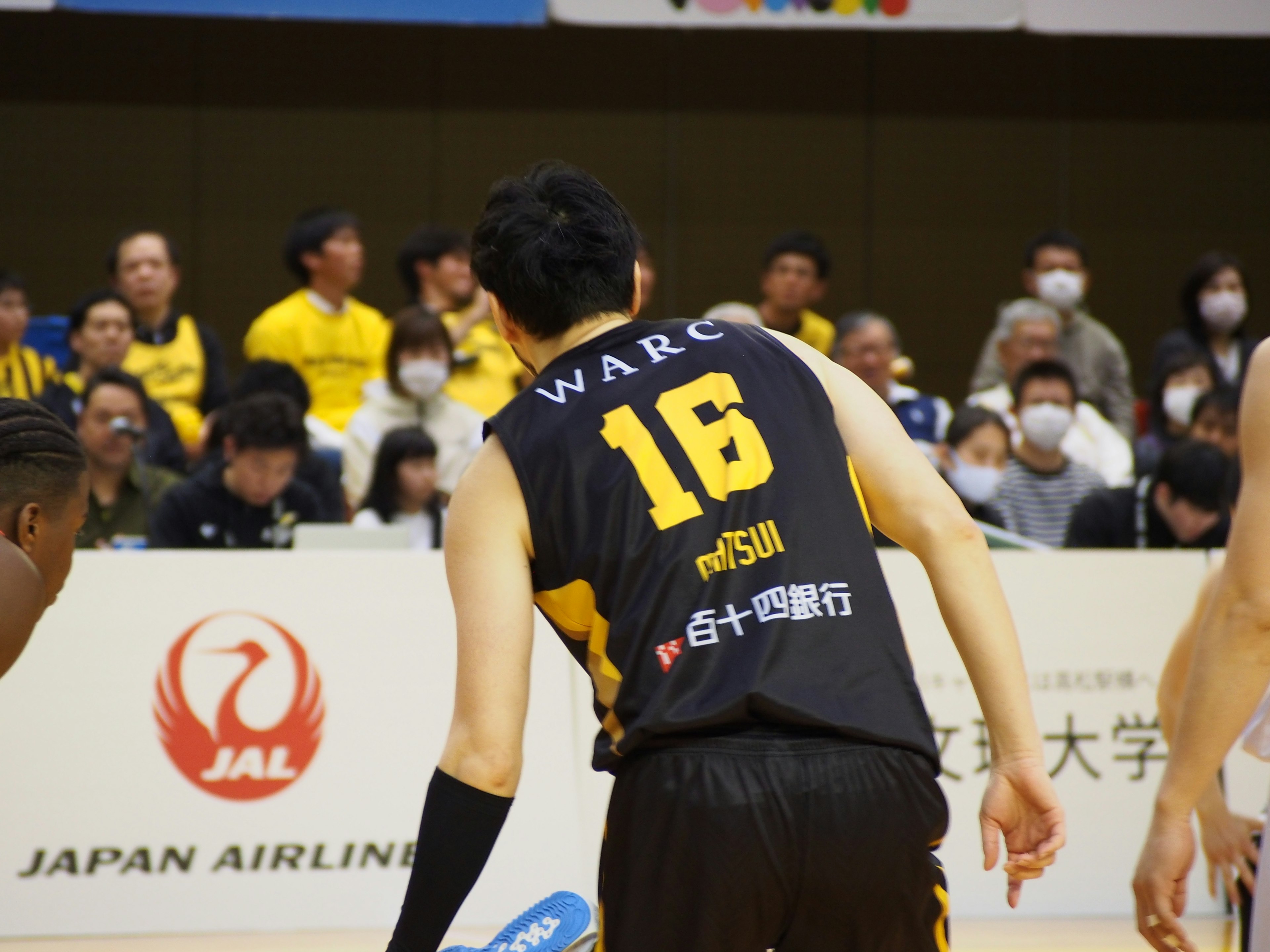 Giocatore di basket con la maglia numero 16 che gioca con i tifosi sullo sfondo