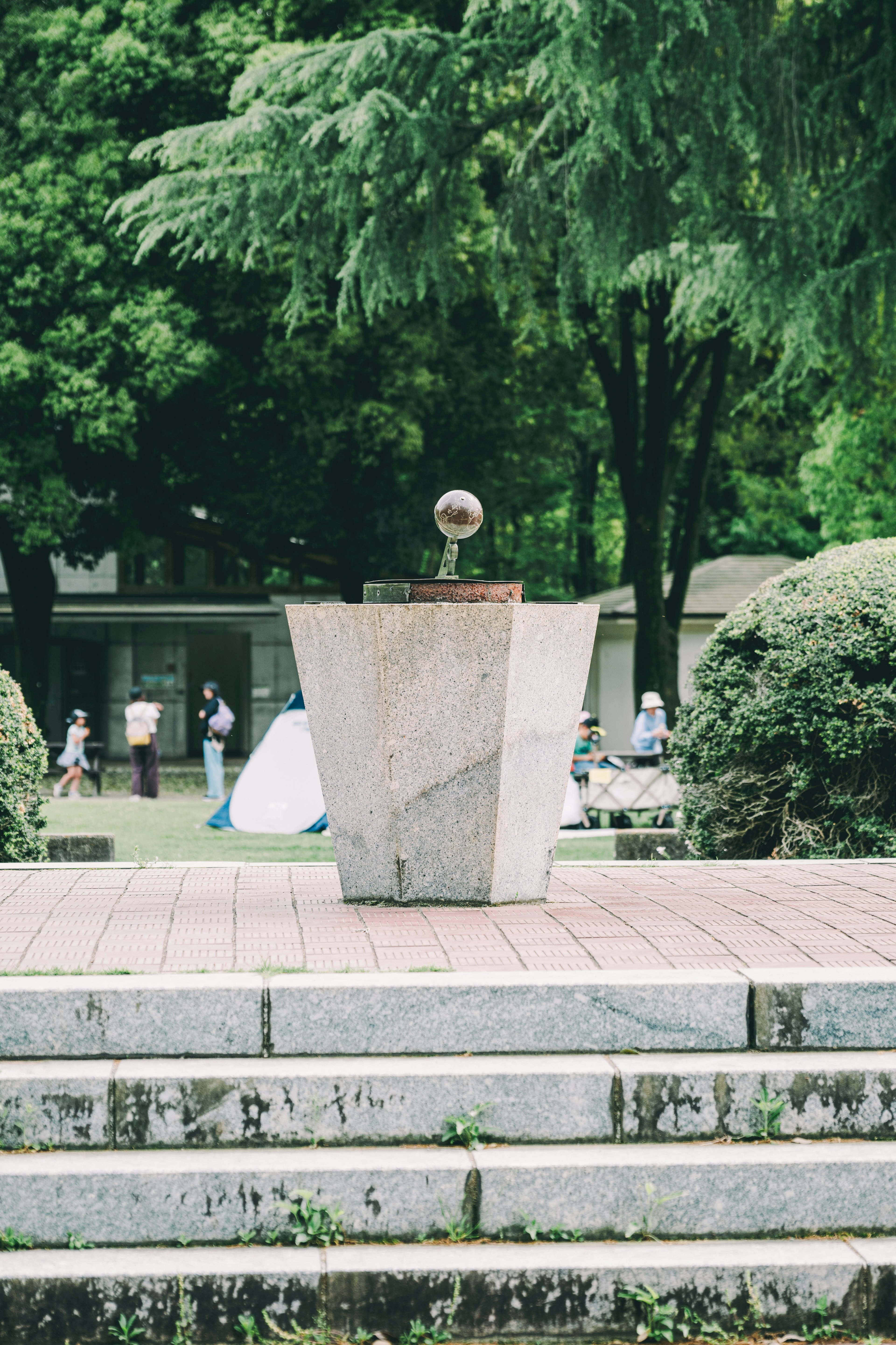 Scultura moderna al centro di un parco circondata da alberi verdi