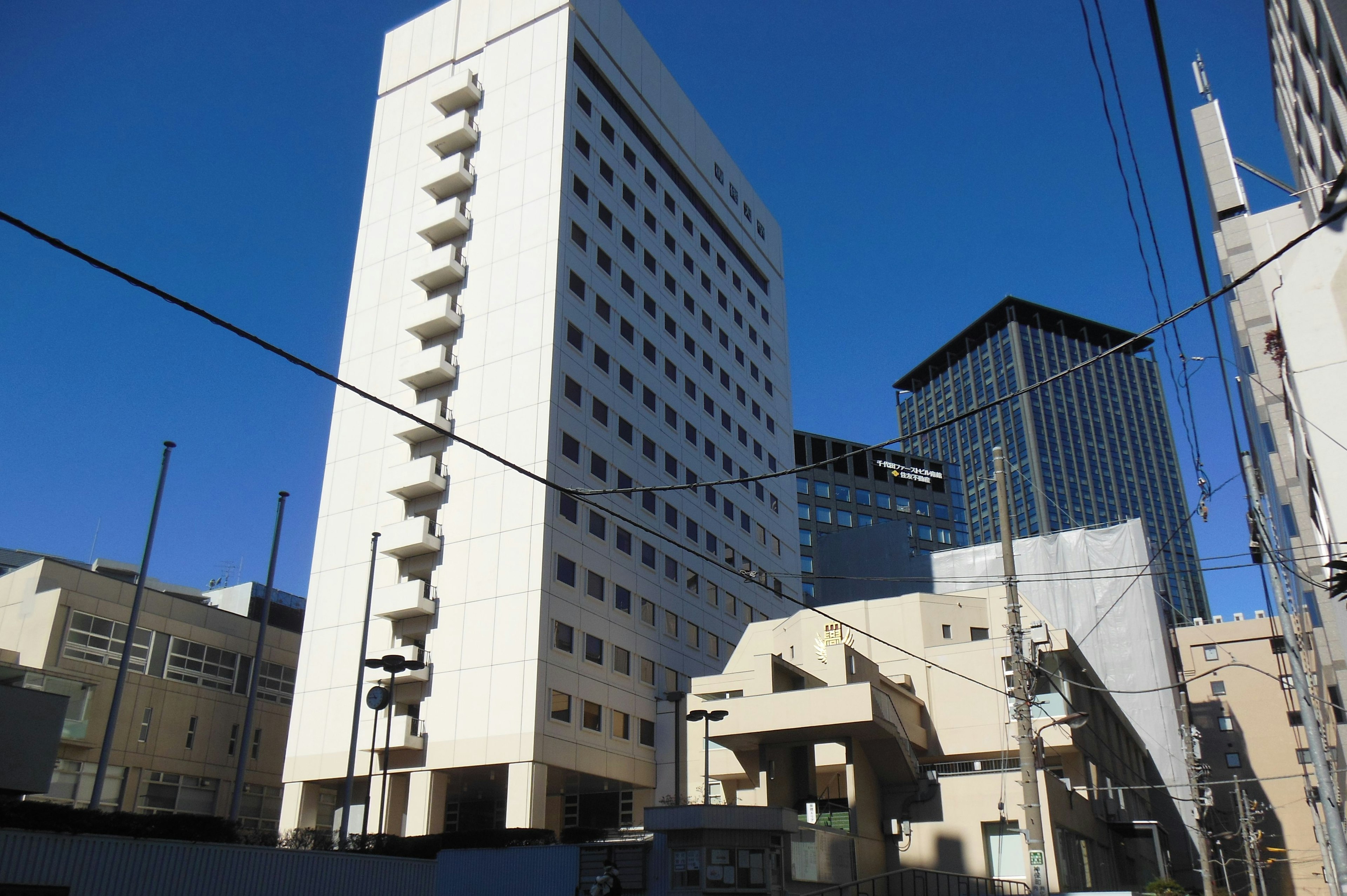 Cityscape featuring a white building and modern skyscrapers under a clear blue sky