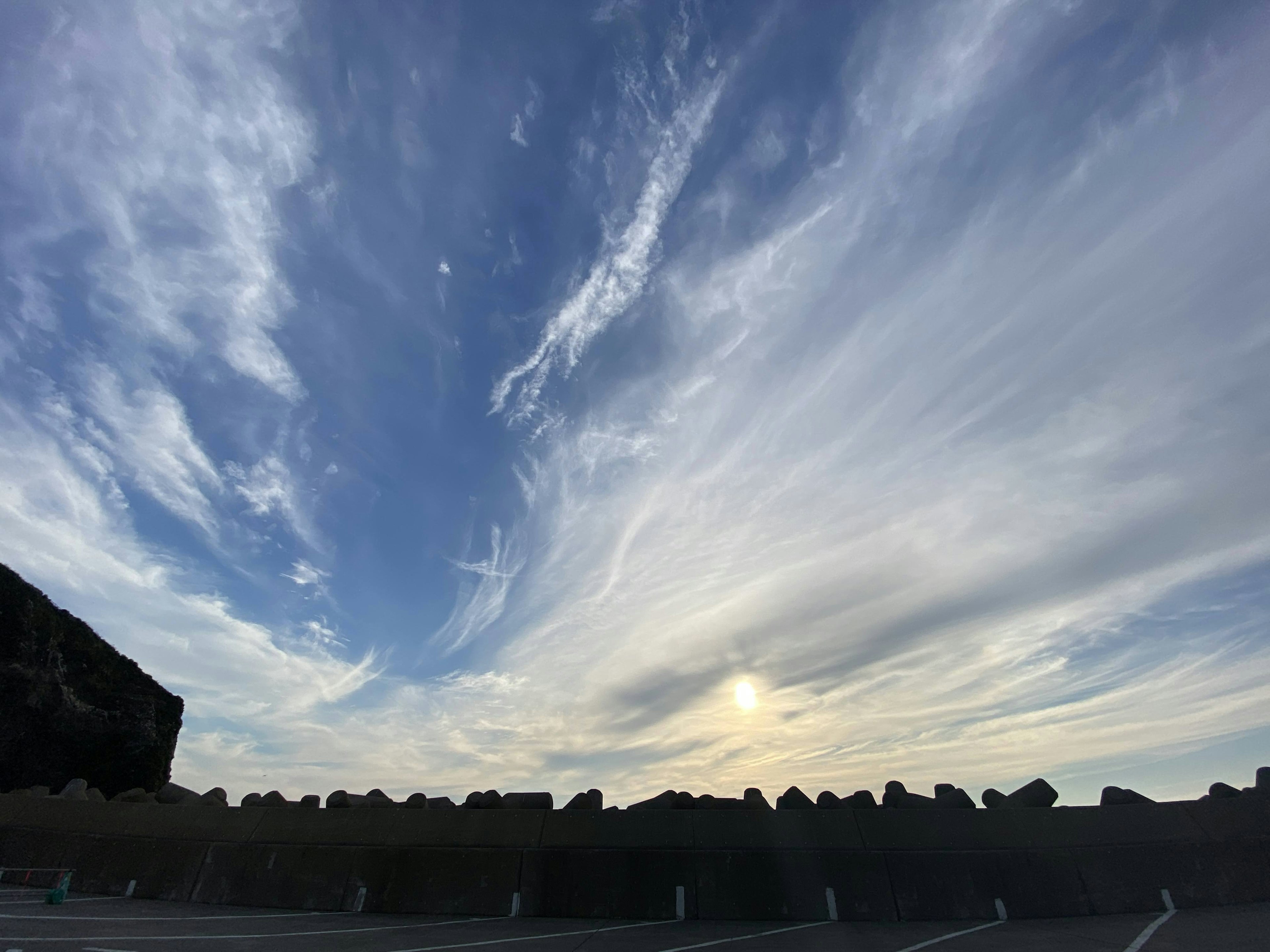 Weitläufiger Himmel mit dünnen Wolken und untergehender Sonne