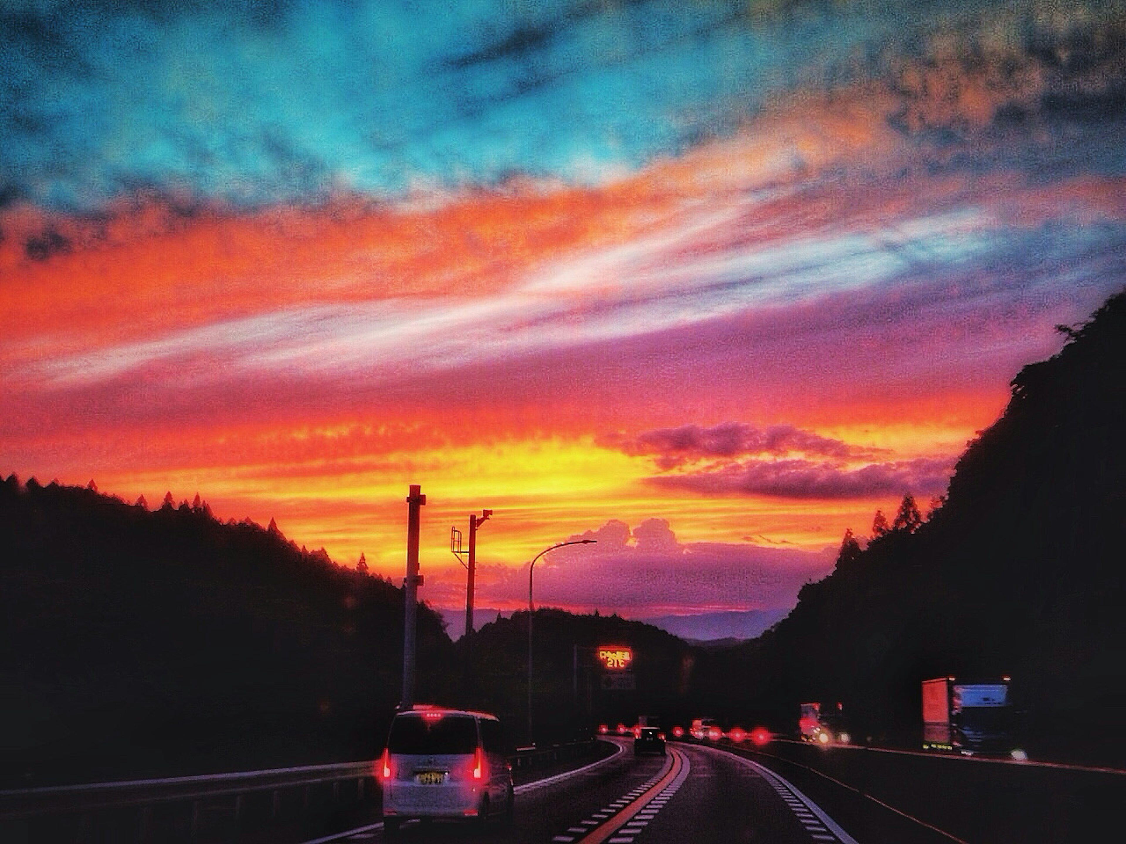 Una impresionante escena de atardecer con una carretera en primer plano y un cielo vibrante de naranja y púrpura