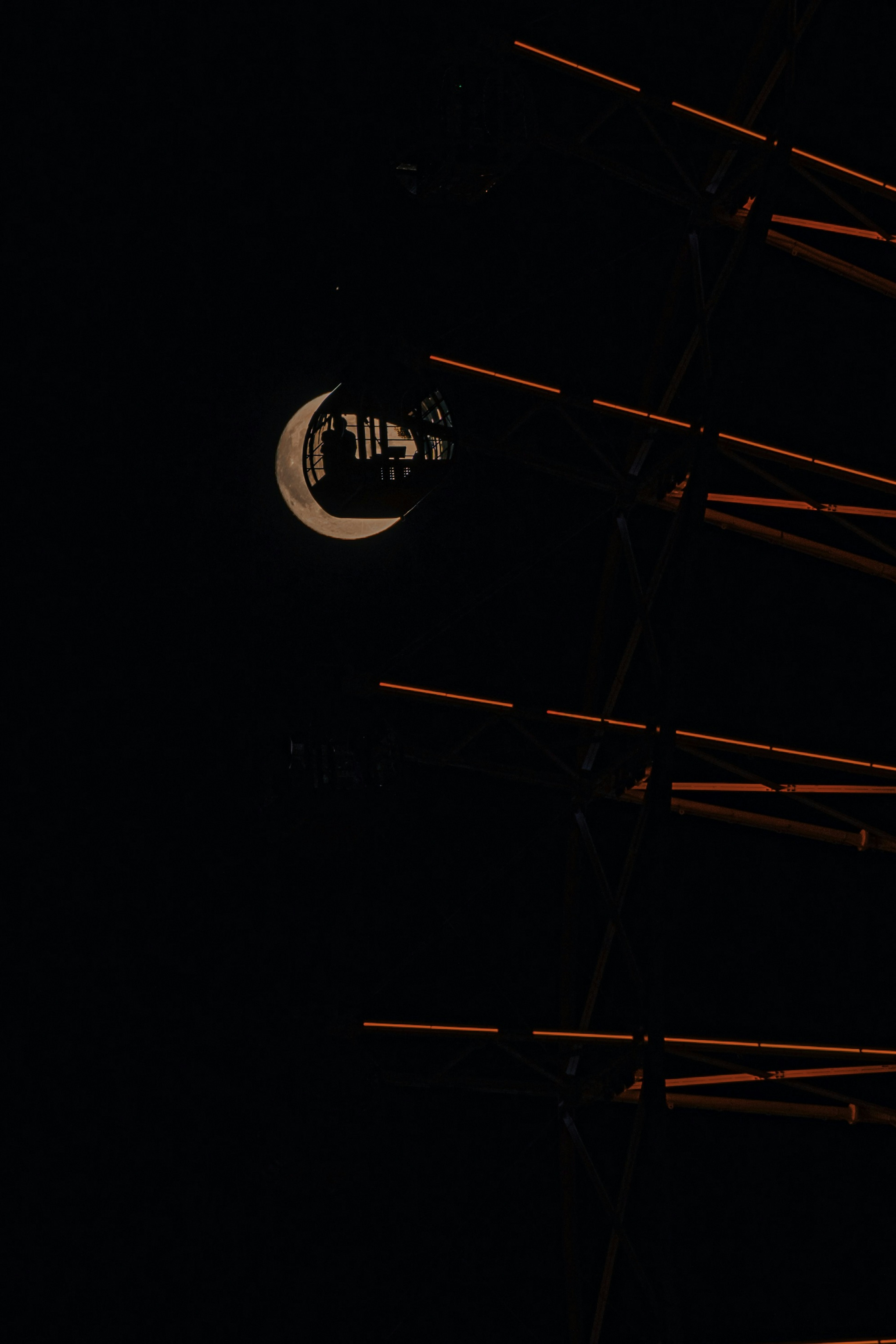 Image présentant un croissant de lune sur un fond noir avec des lignes orange