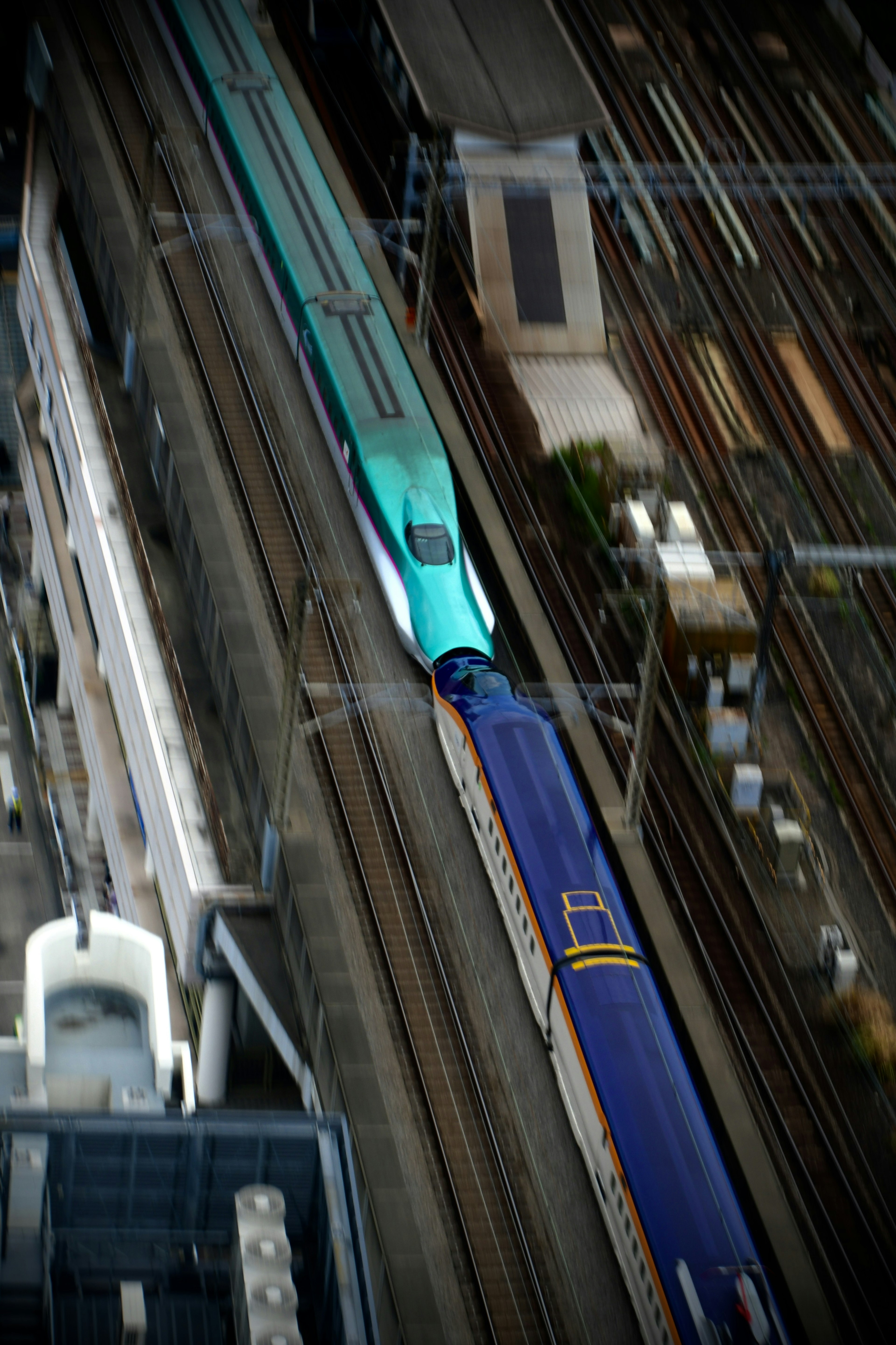 Aerial view of a high-speed train and a conventional train intersecting on railway tracks