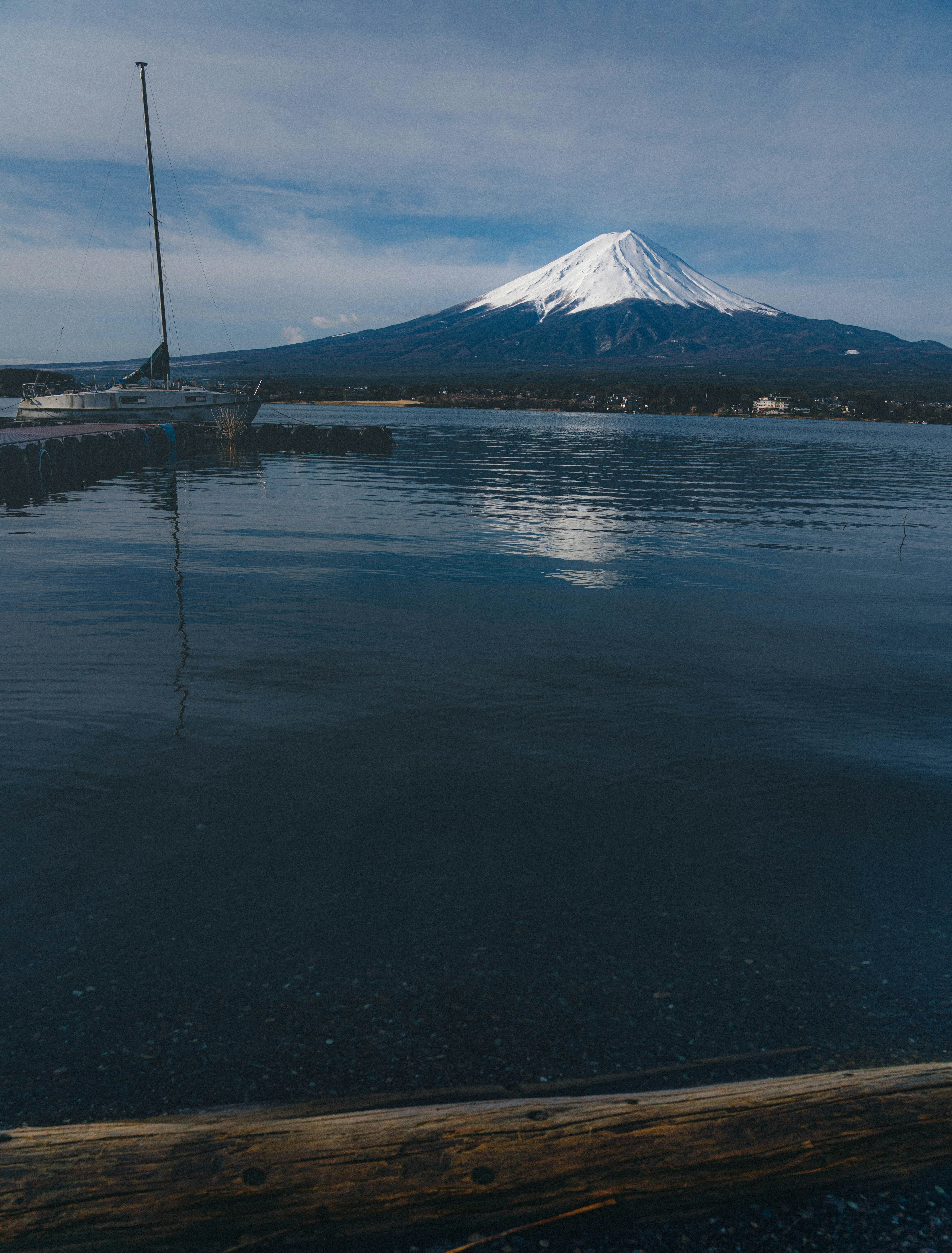 静かな湖面に映る雪をかぶった山とボート