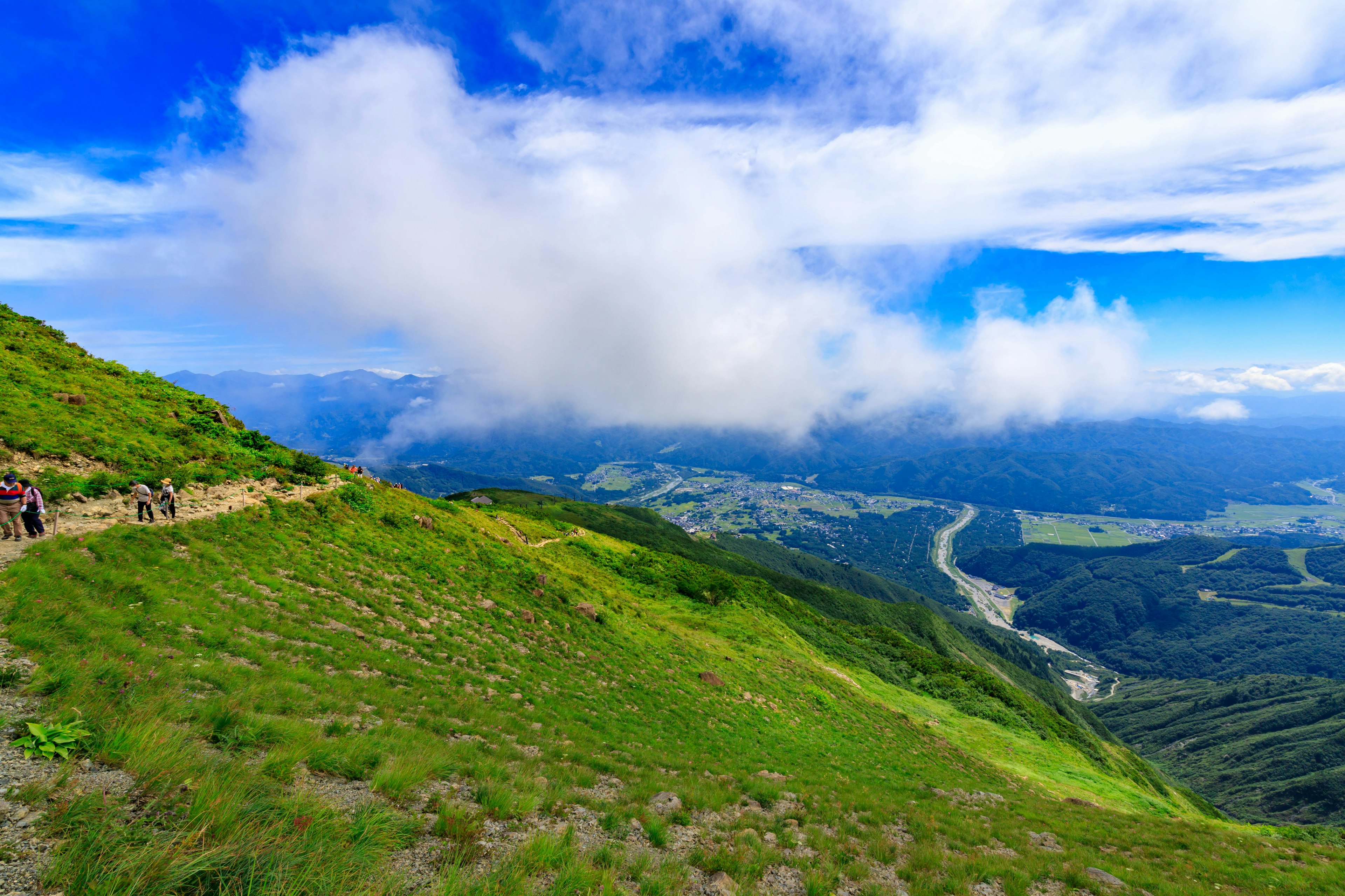 山景蓝天和云朵绿色草地和可见的山谷