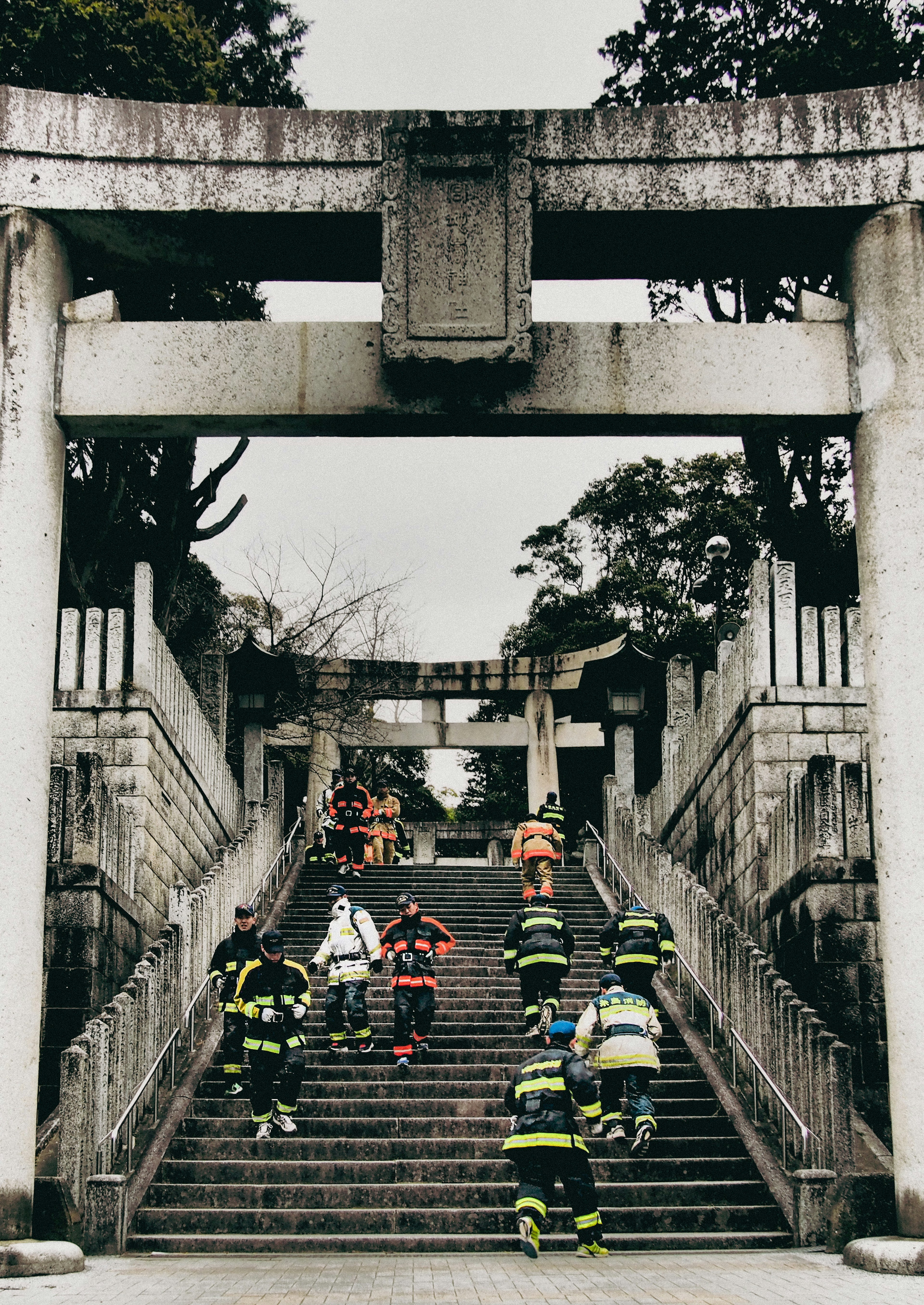 階段を上る消防士たちと鳥居のある風景