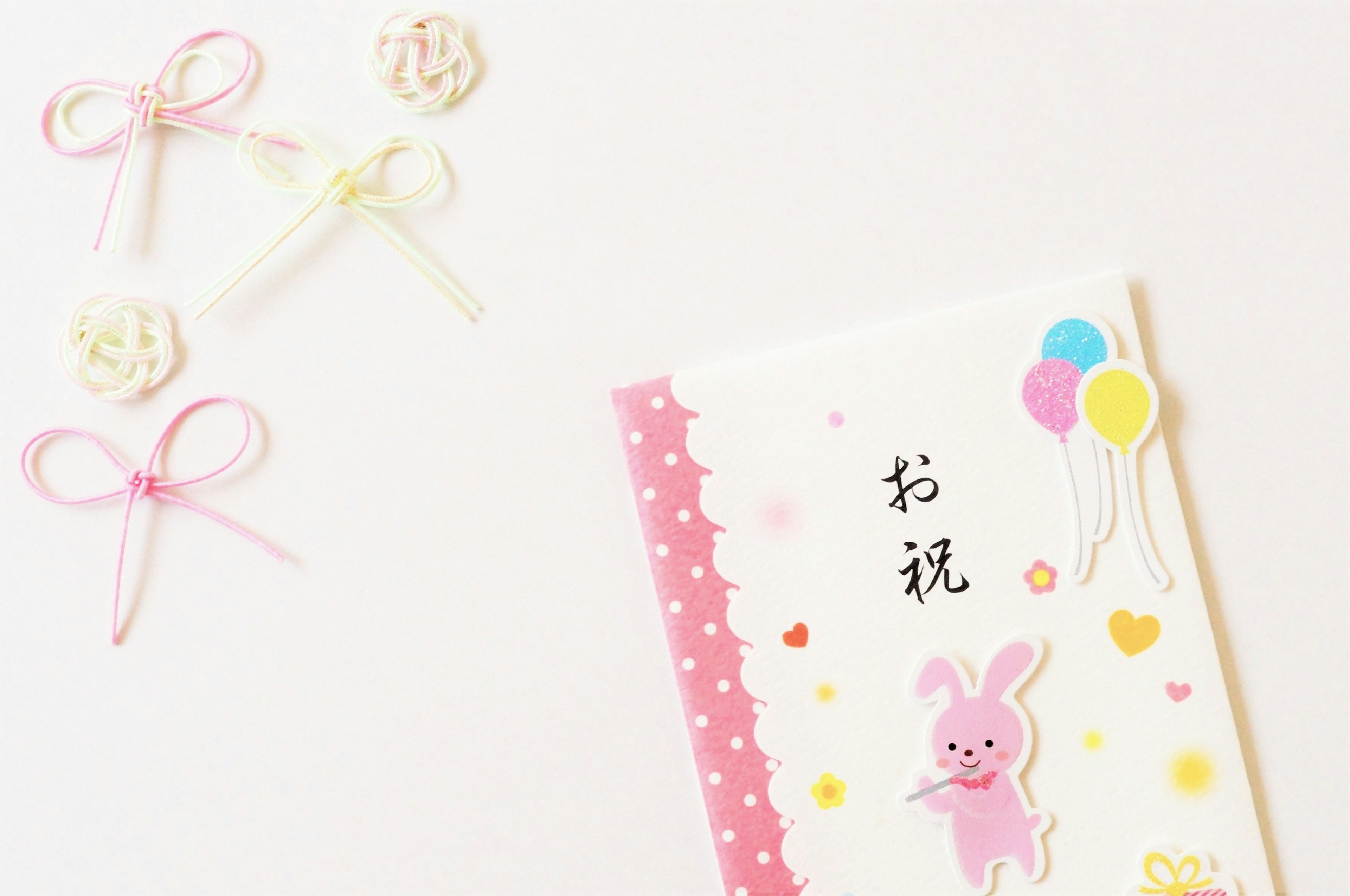 Colorful card featuring a rabbit illustration and balloons with decorative ribbons