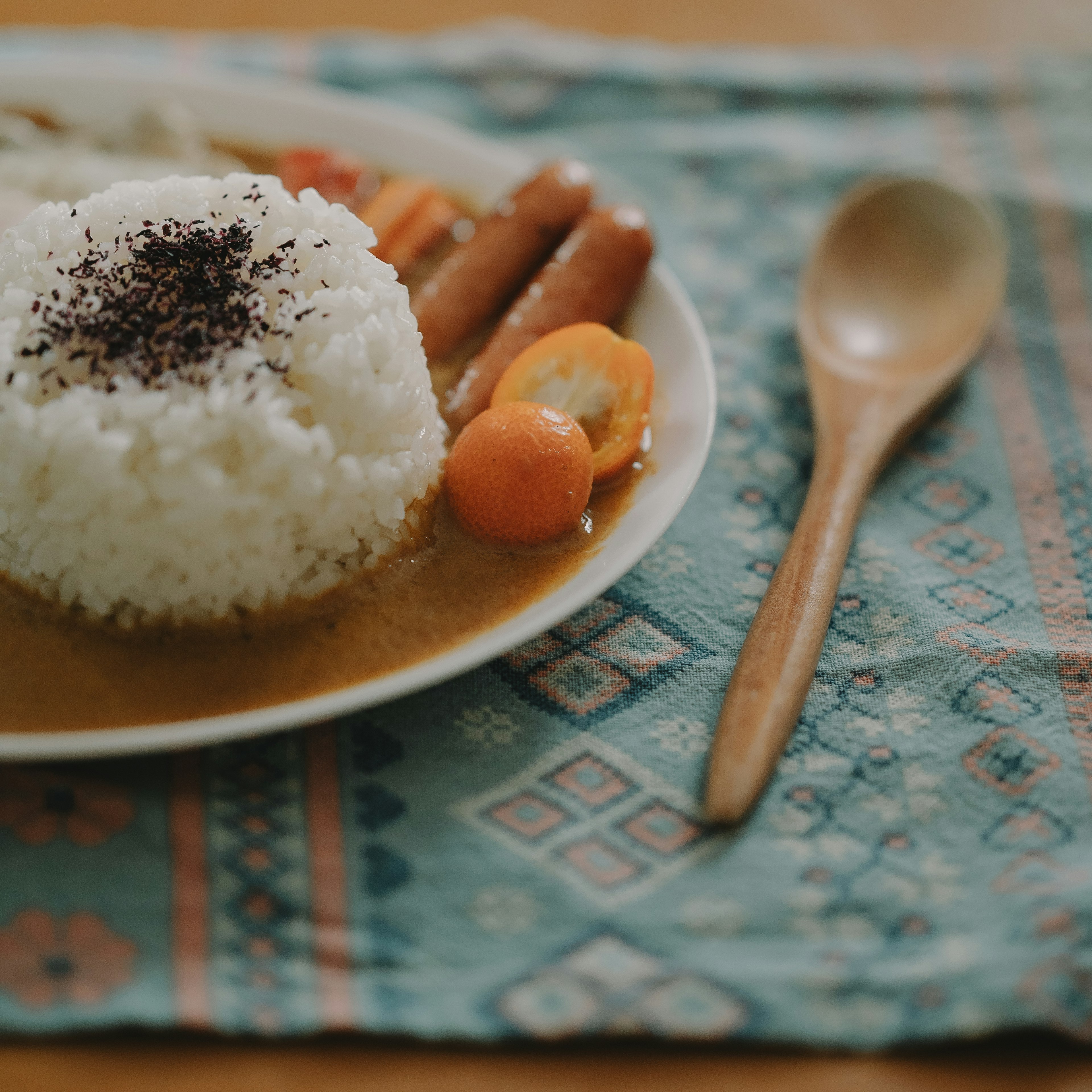 Ein Teller Curryreis mit weißem Reis, der mit schwarzem Belag und buntem Gemüse garniert ist