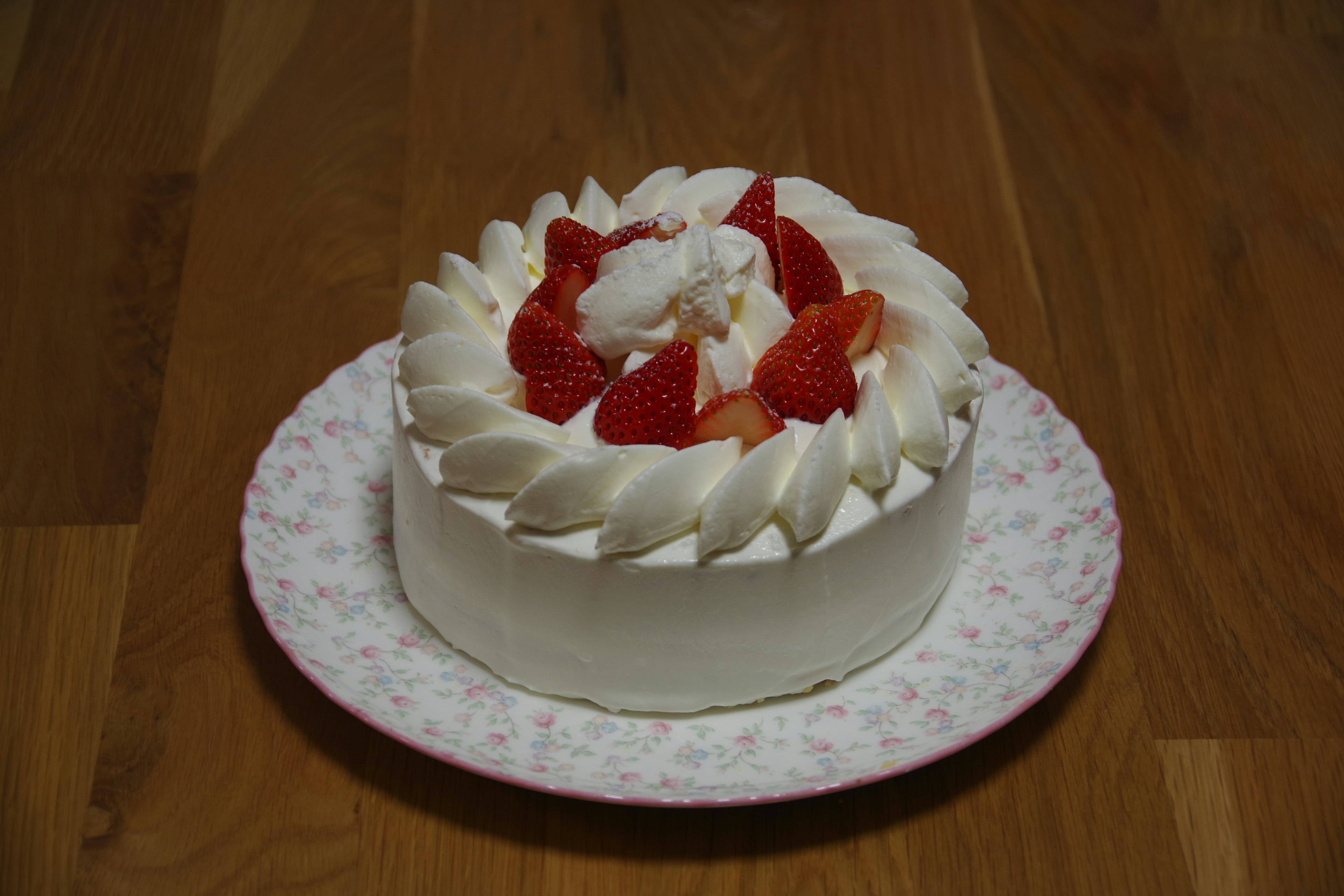 A cake topped with white cream and strawberries