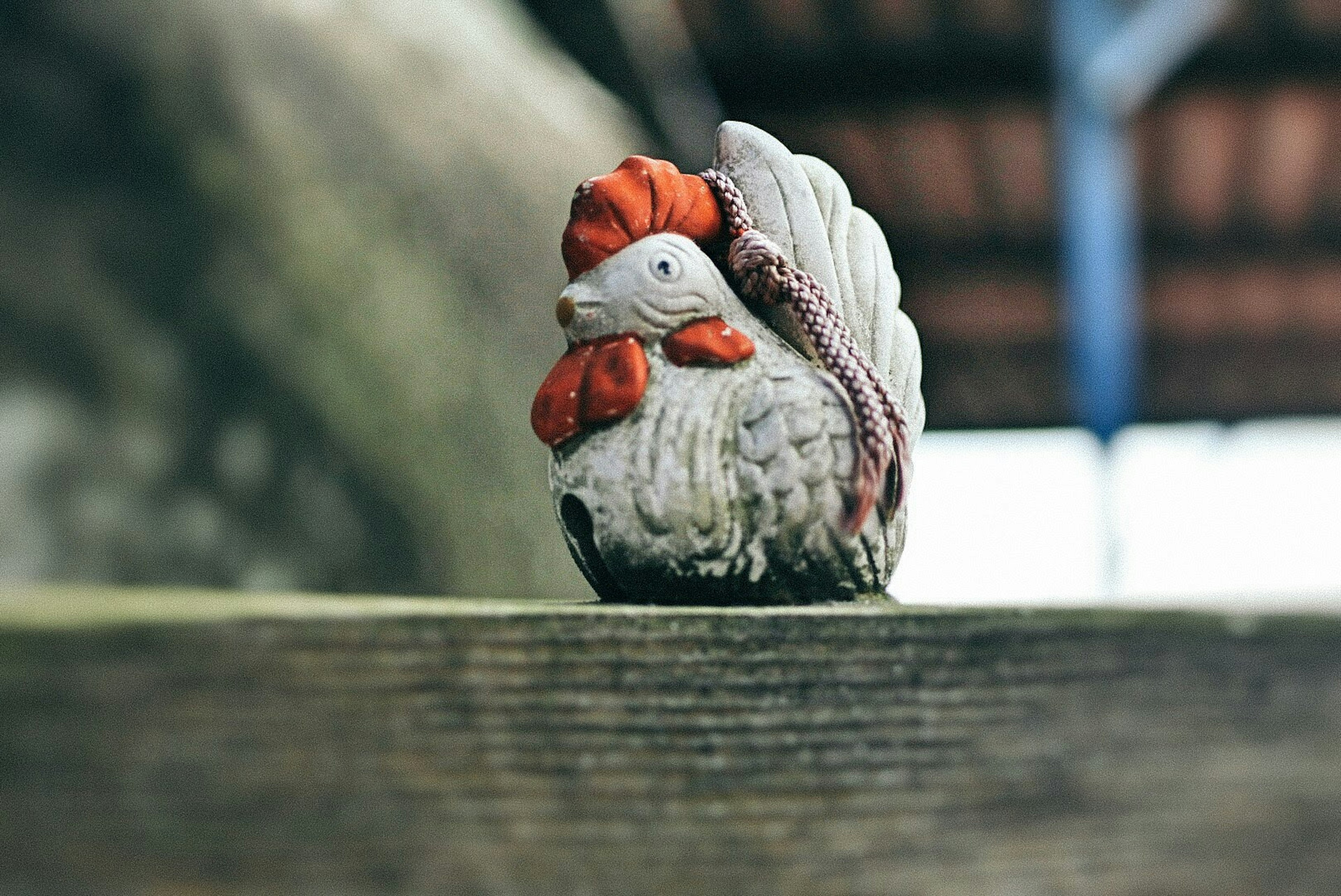 Un pequeño gallo de cerámica colocado sobre una superficie de madera