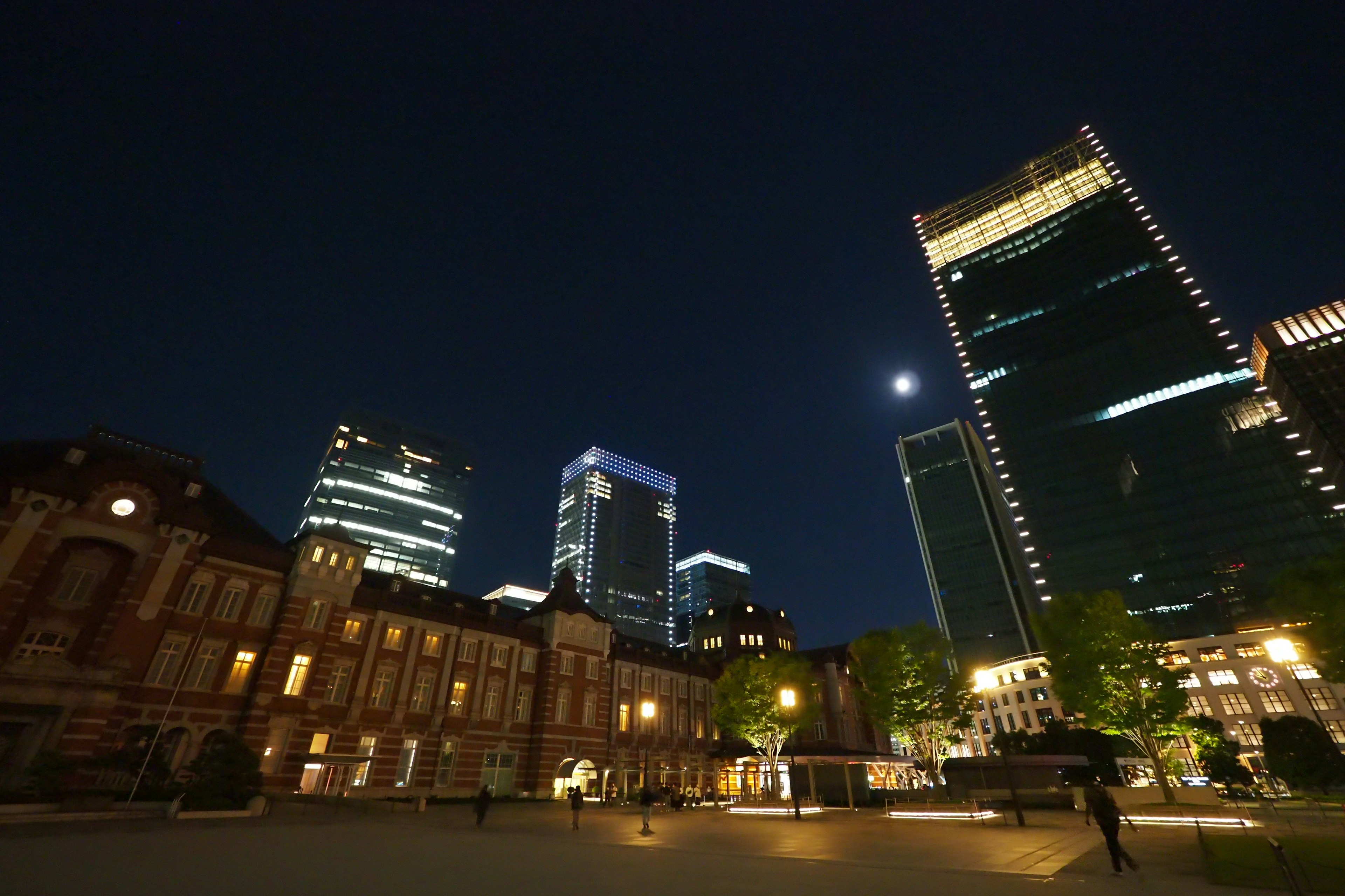 東京駅の歴史的な建物と現代的な高層ビルが夜空の下に立っている