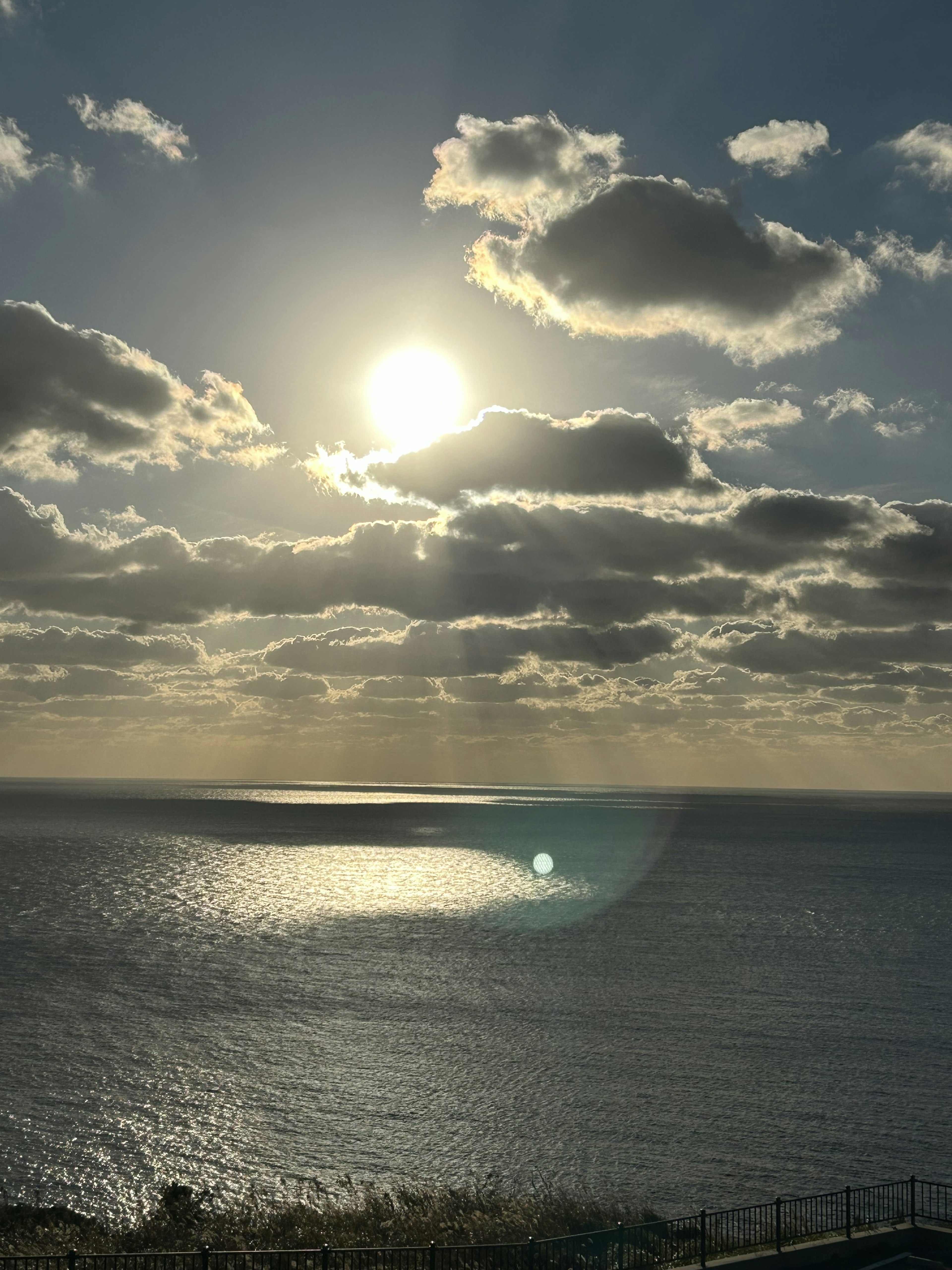 Scenic view of the ocean with a bright sun and fluffy clouds