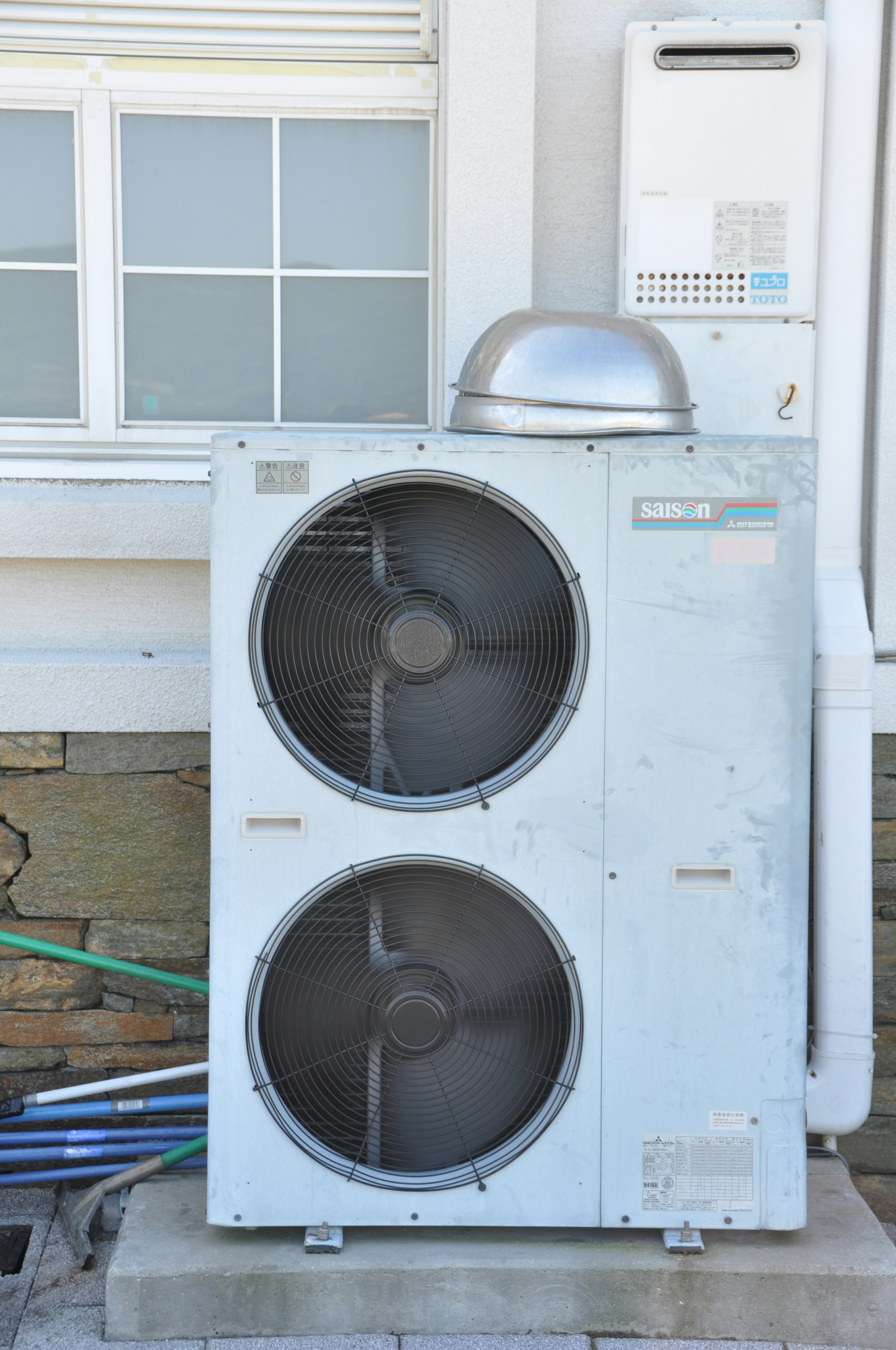 Outdoor unit of an air conditioning system featuring two fans and a metal cover