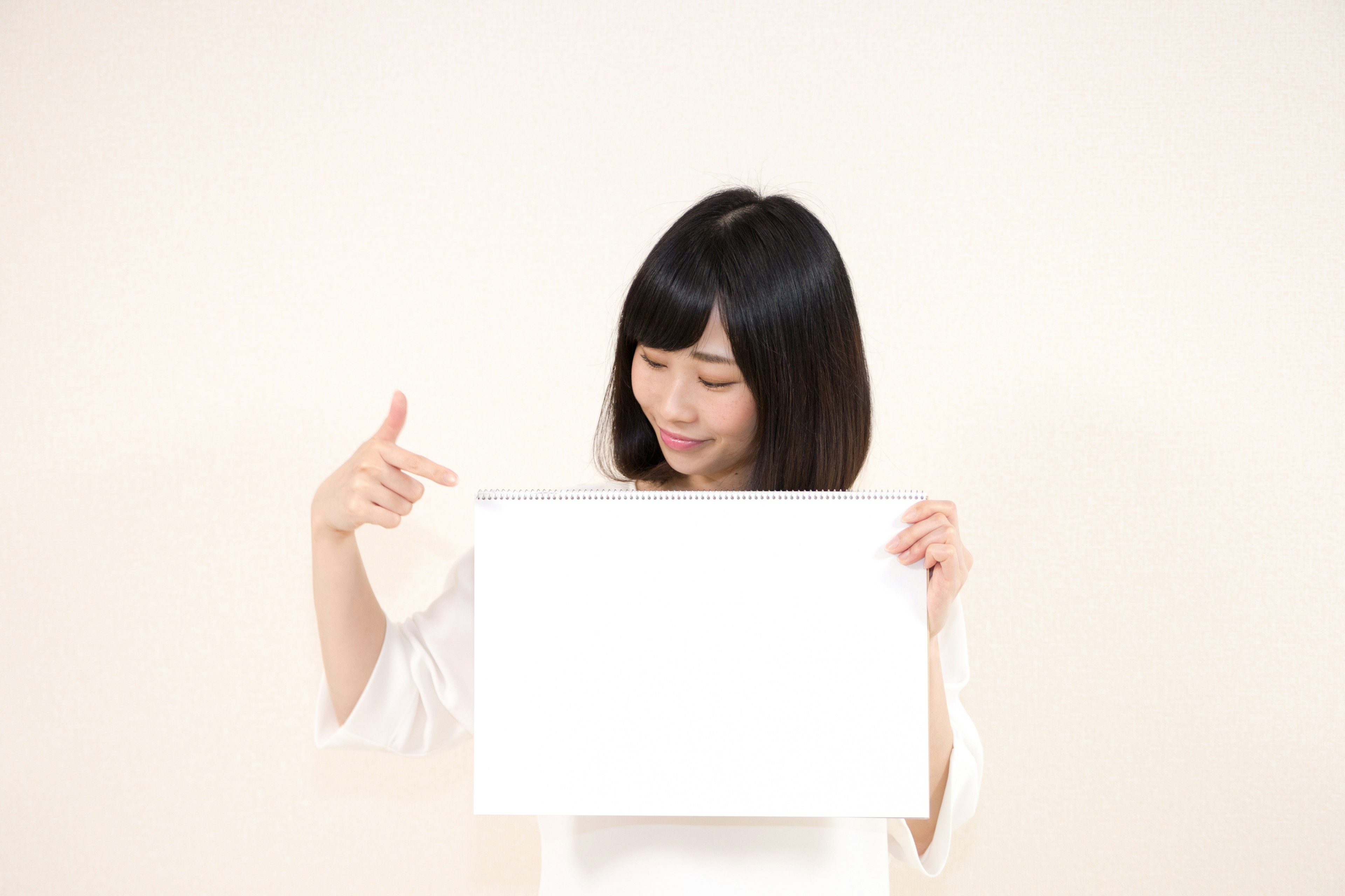 Young woman holding a blank white board in front of a white background