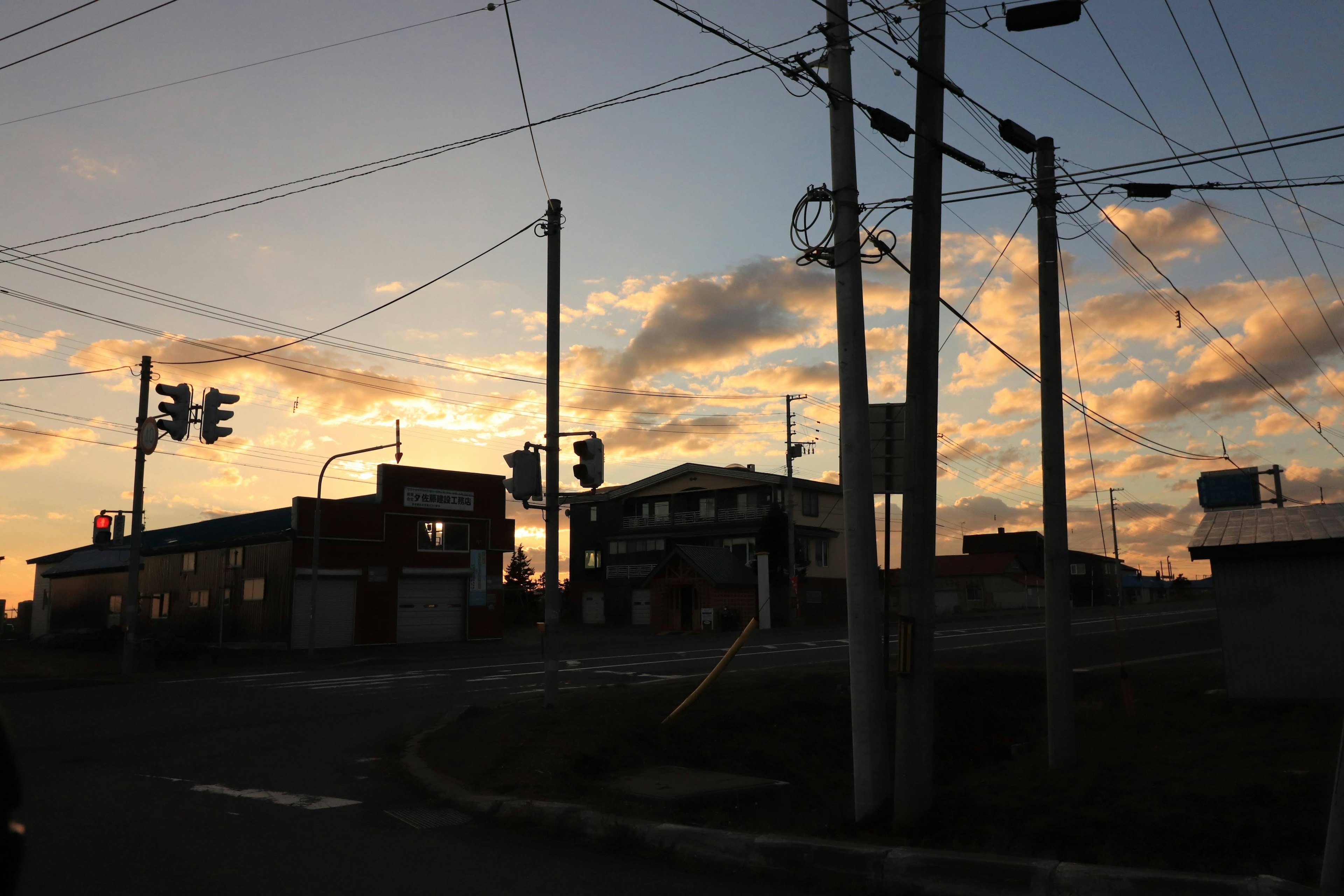 Paisaje de esquina de calle iluminado por el atardecer semáforos y postes de servicios públicos en una zona residencial