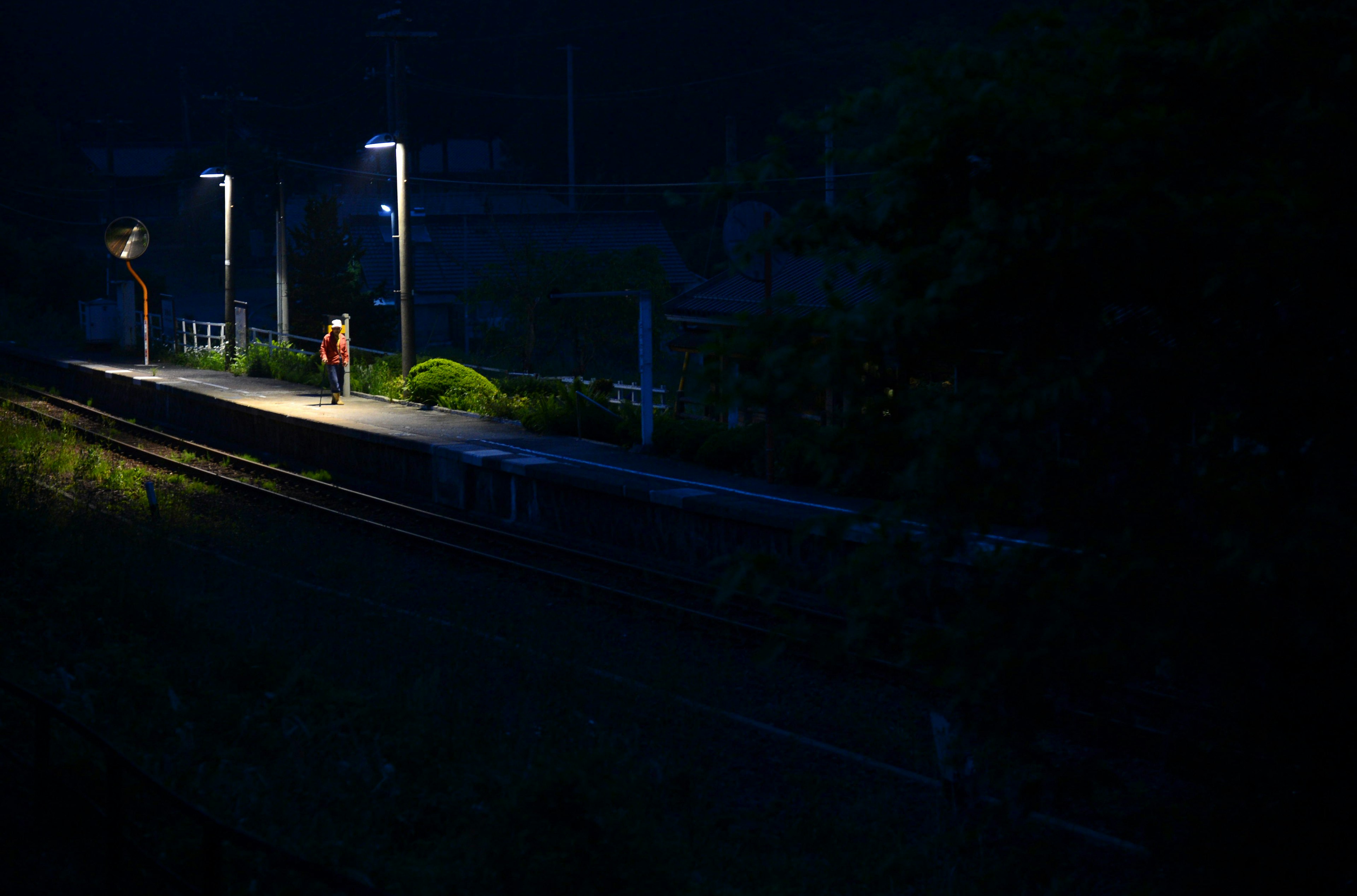 Person steht auf einem dunklen Bahnsteig mit Lichtern