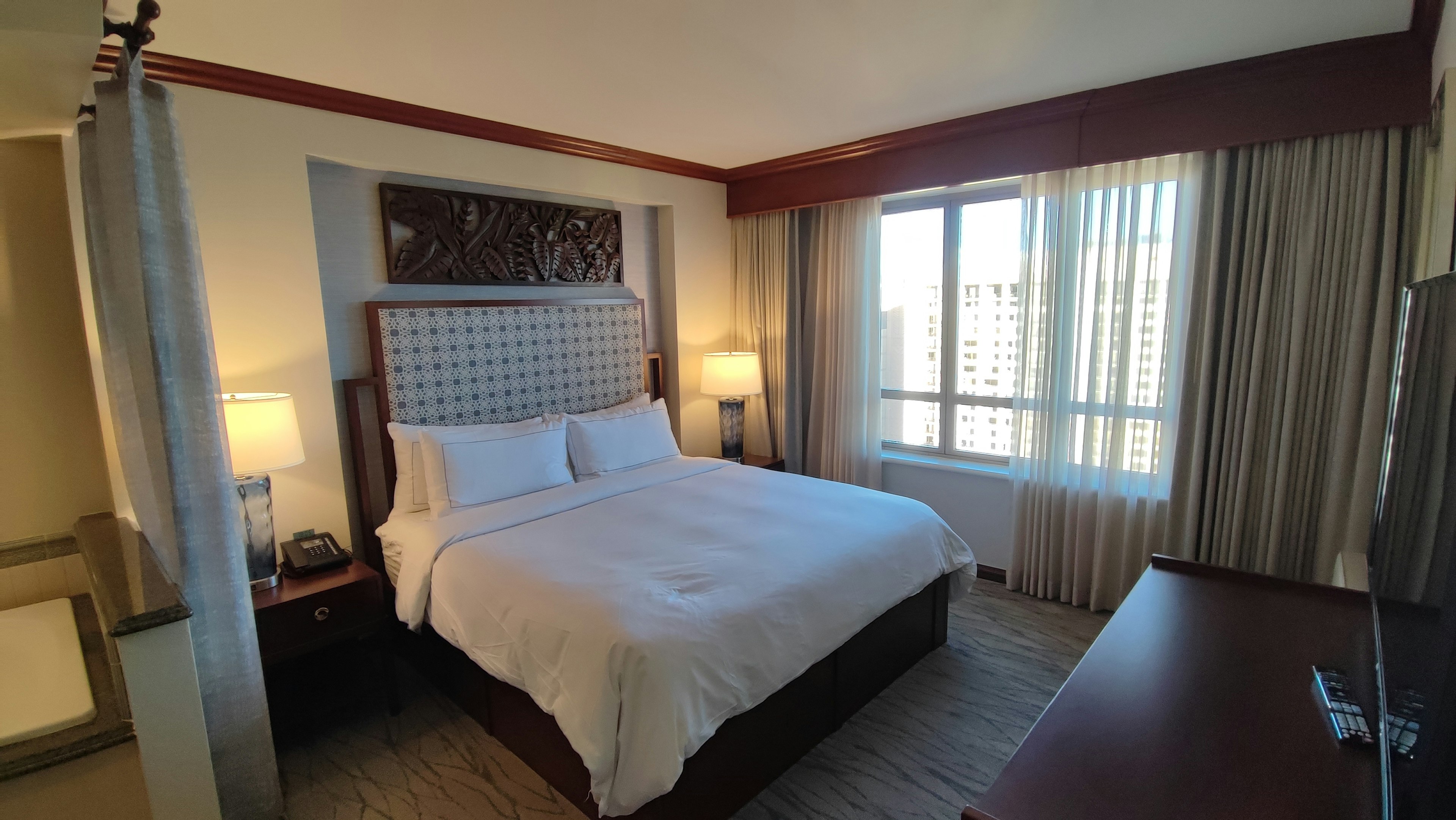 Bright bedroom featuring a large window and a tufted headboard