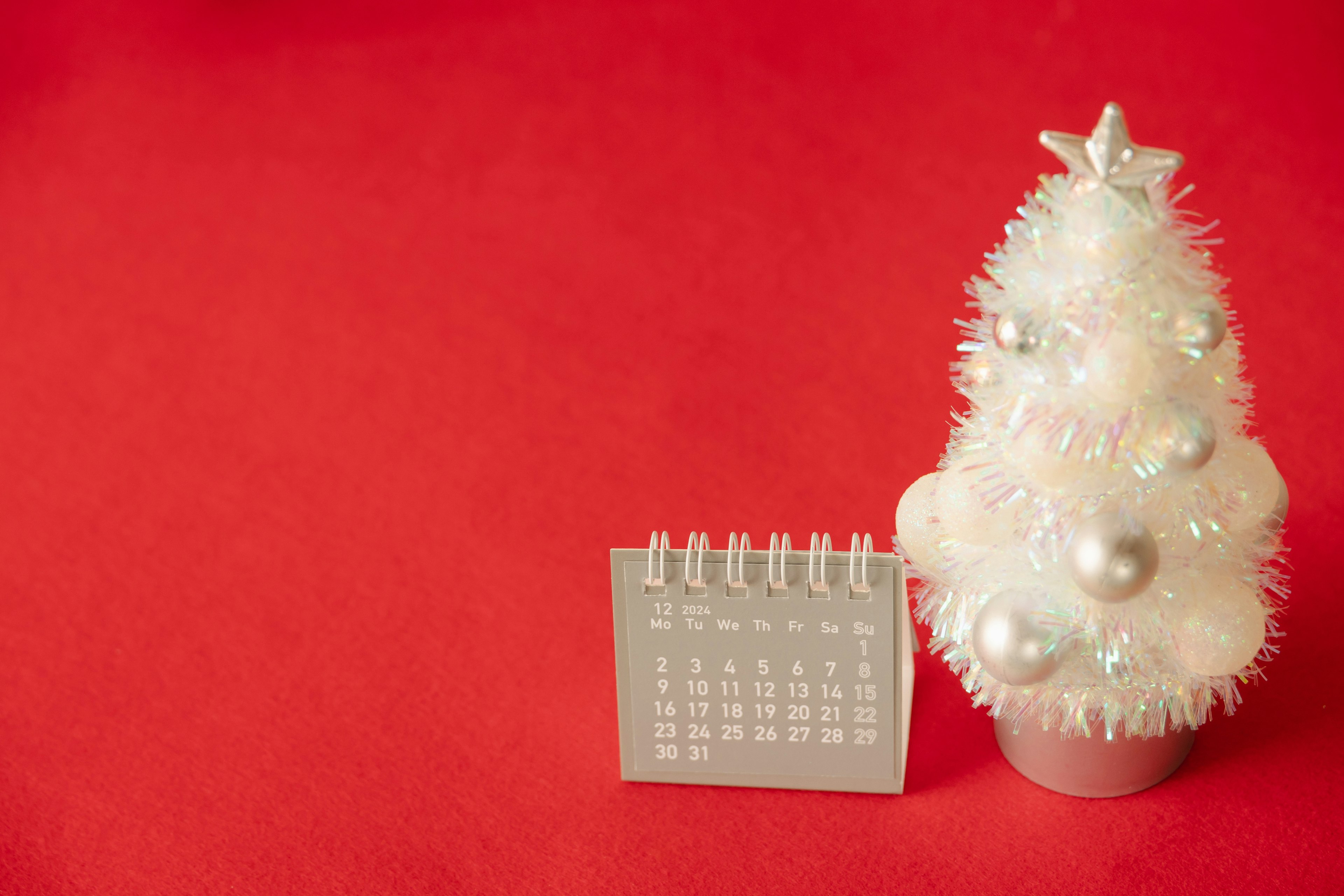 Un árbol de Navidad blanco y un calendario sobre un fondo rojo