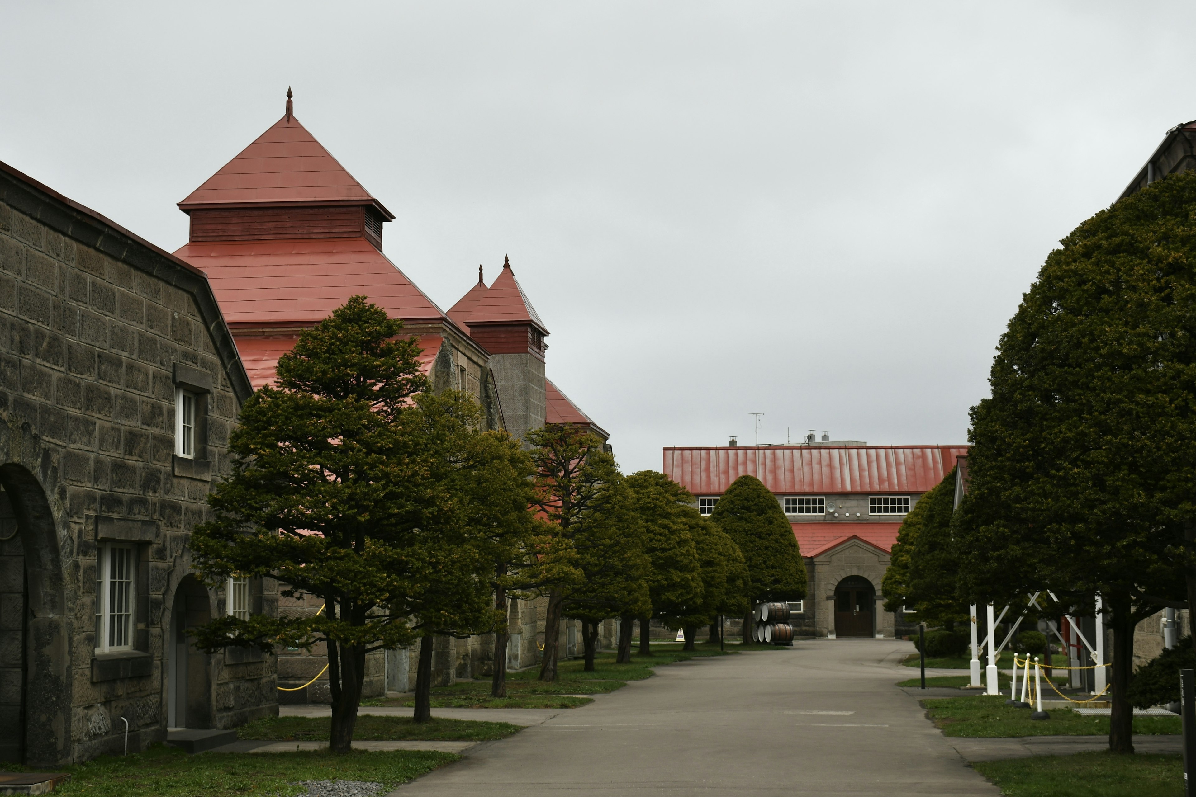 Historische Gebäude mit roten Dächern und ordentlich angeordneten Bäumen entlang des Weges