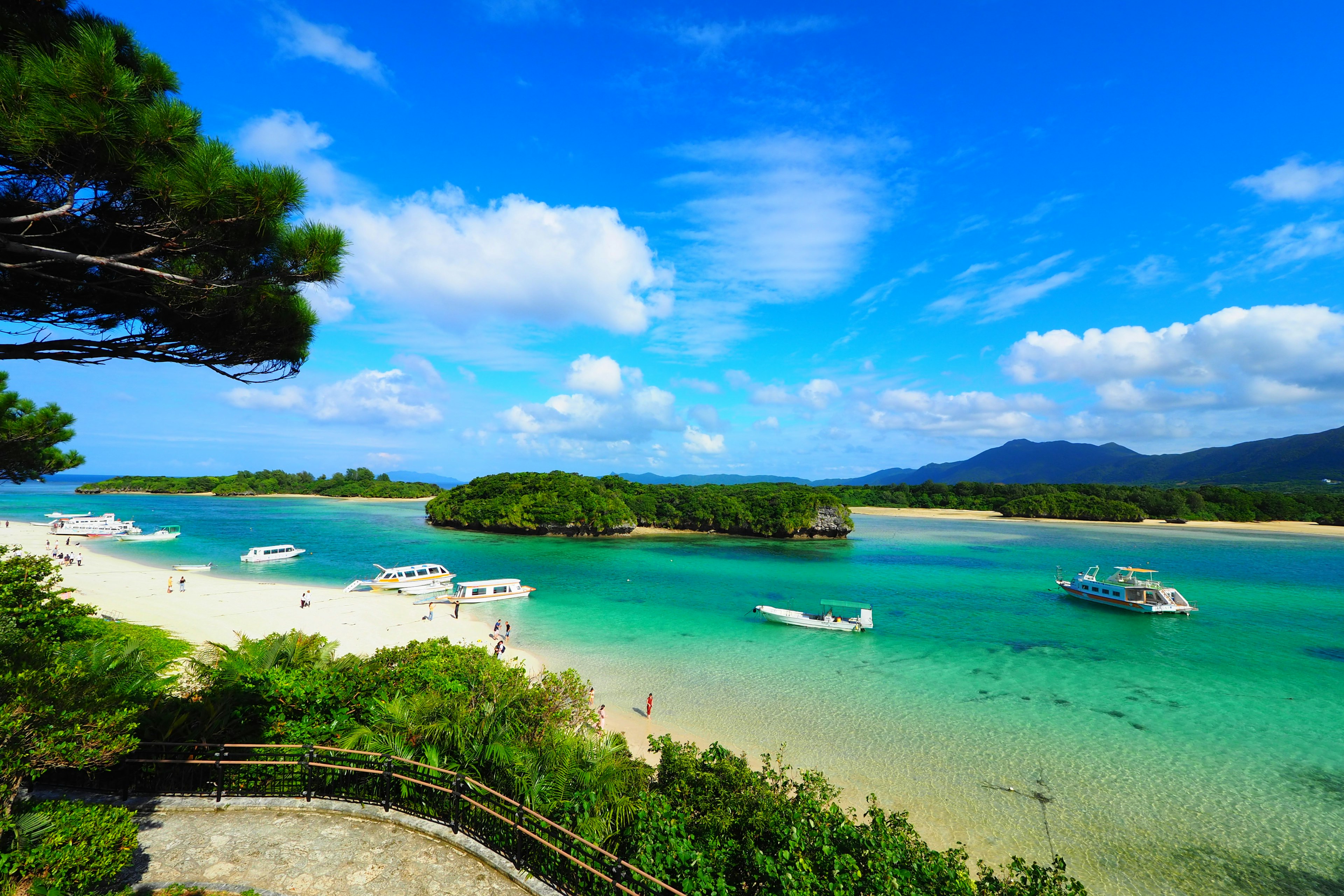 ทิวทัศน์อันสวยงามที่มีทะเลและท้องฟ้าสีฟ้า มีเรือและชายหาดทรายขาว