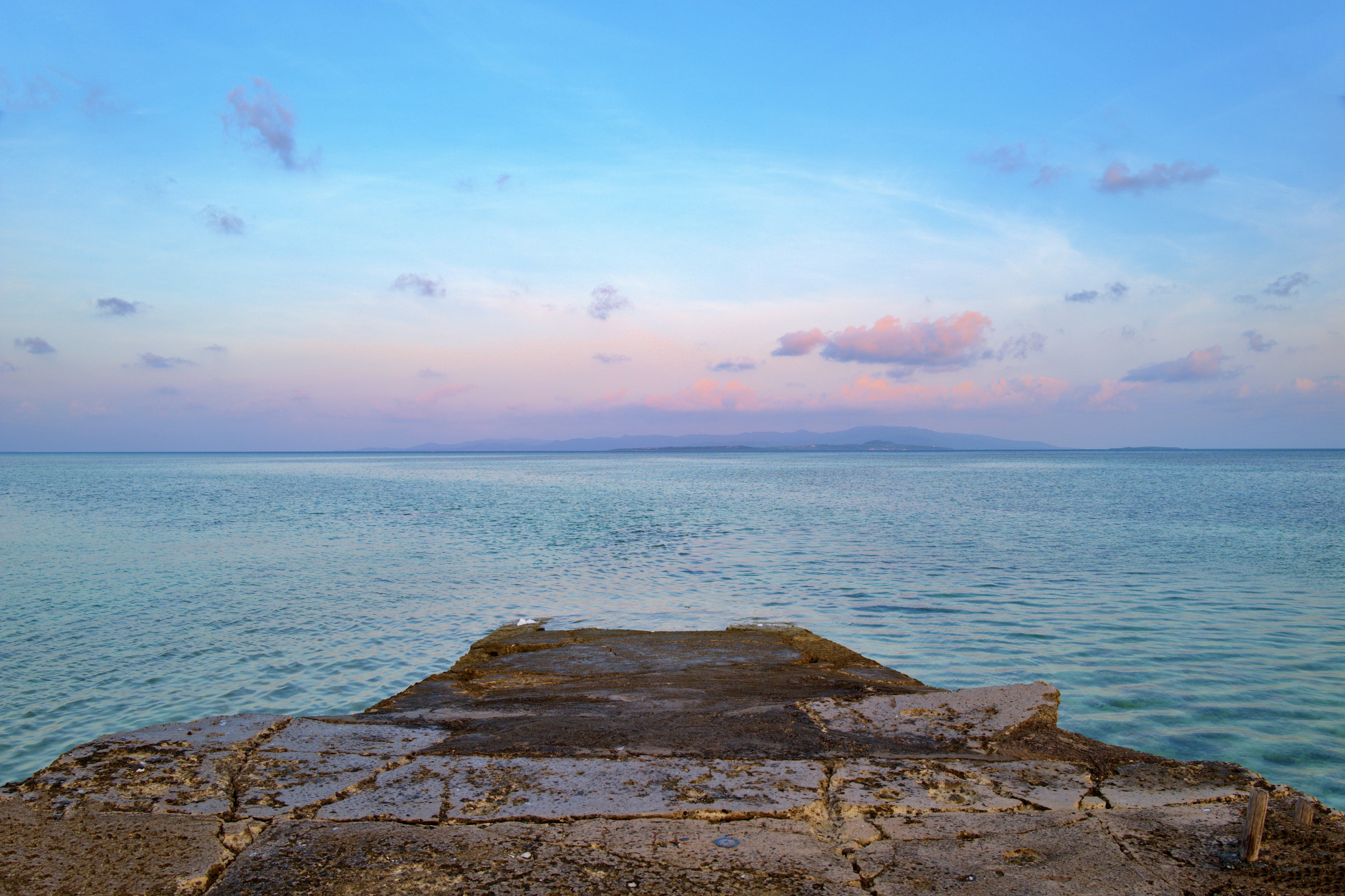 Vista escénica de un muelle que se extiende hacia aguas tranquilas con un cielo degradado