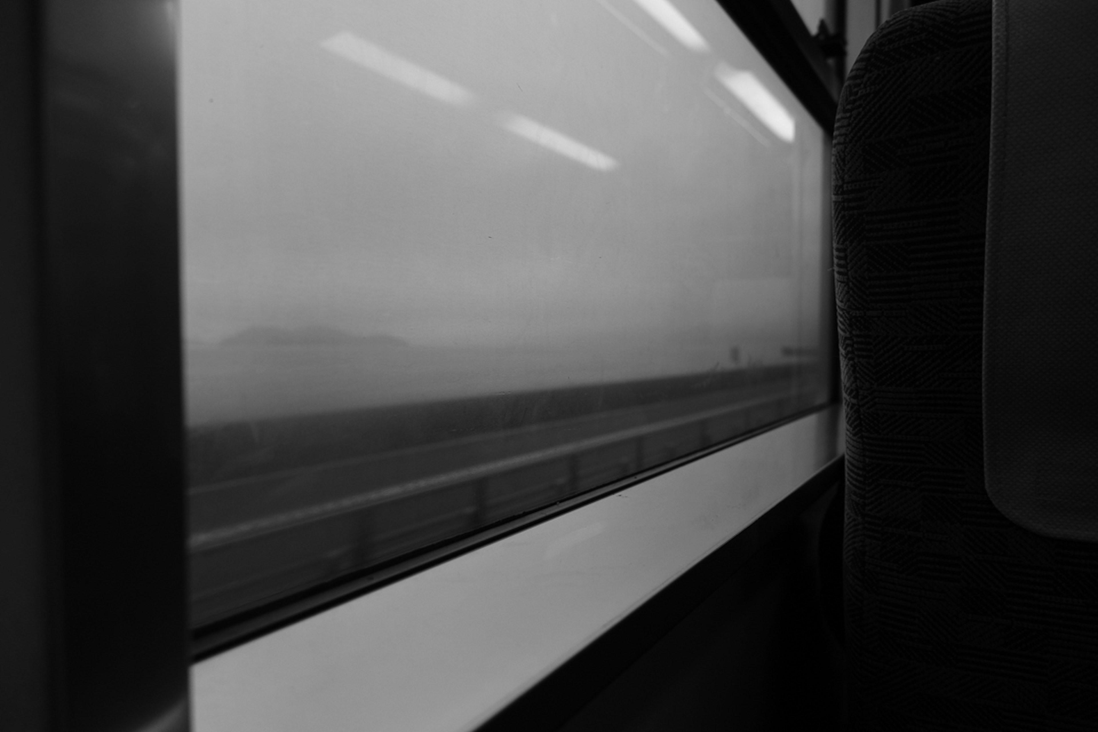 Schwarzweißansicht aus einem Zugfenster mit verschwommener Landschaft