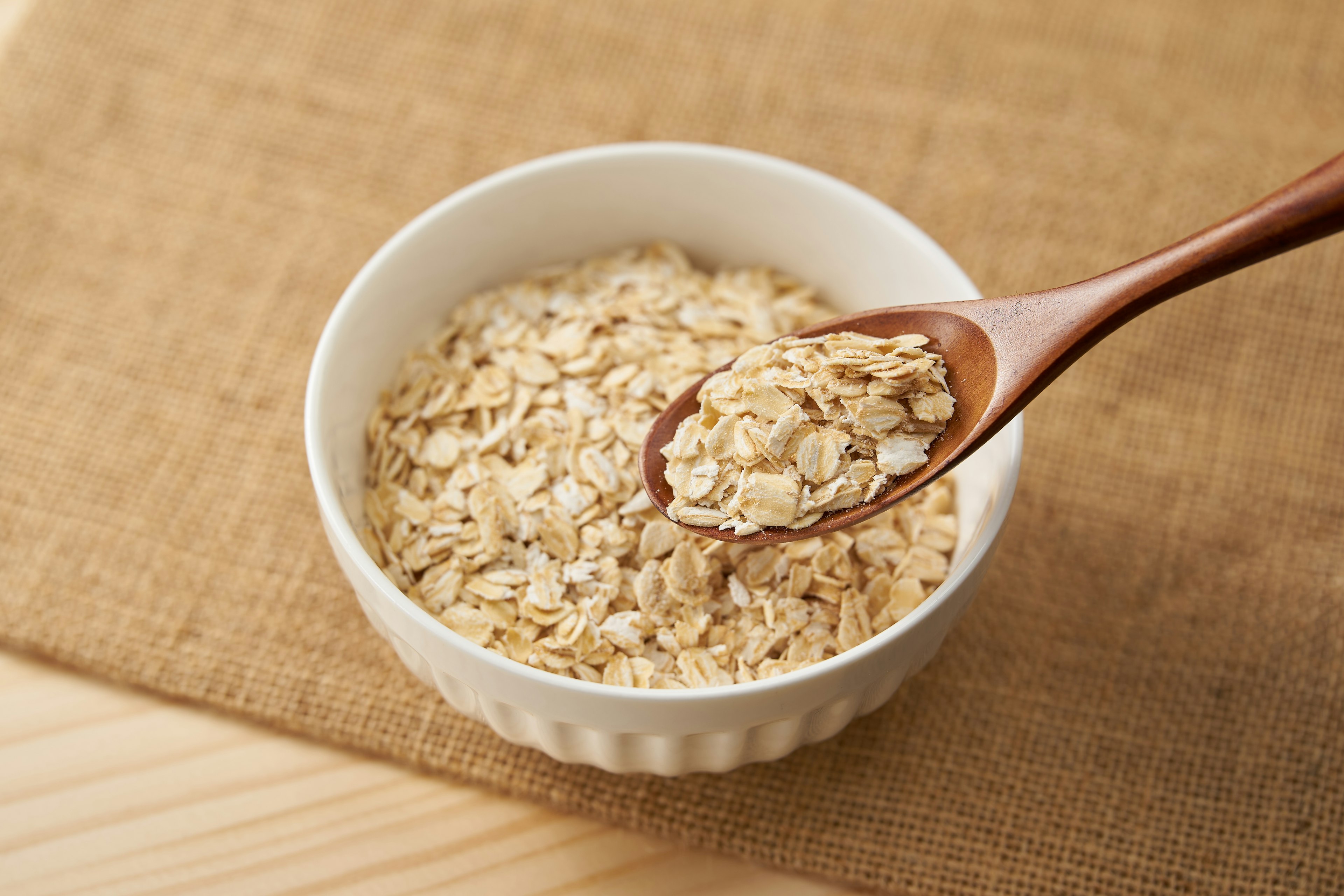 Fiocchi d'avena in una ciotola bianca con un cucchiaio di legno