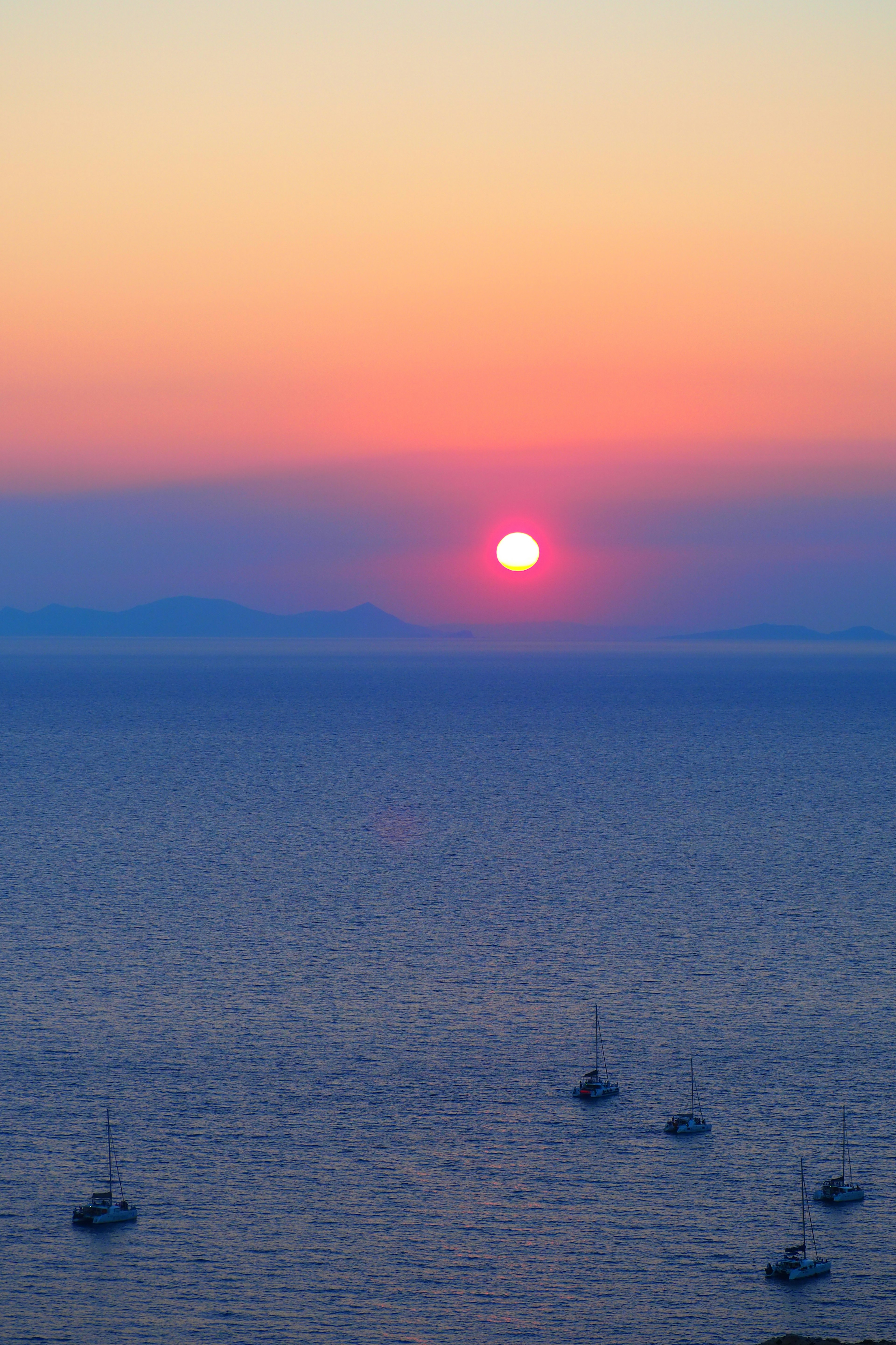 Atardecer sobre el océano con siluetas de barcos