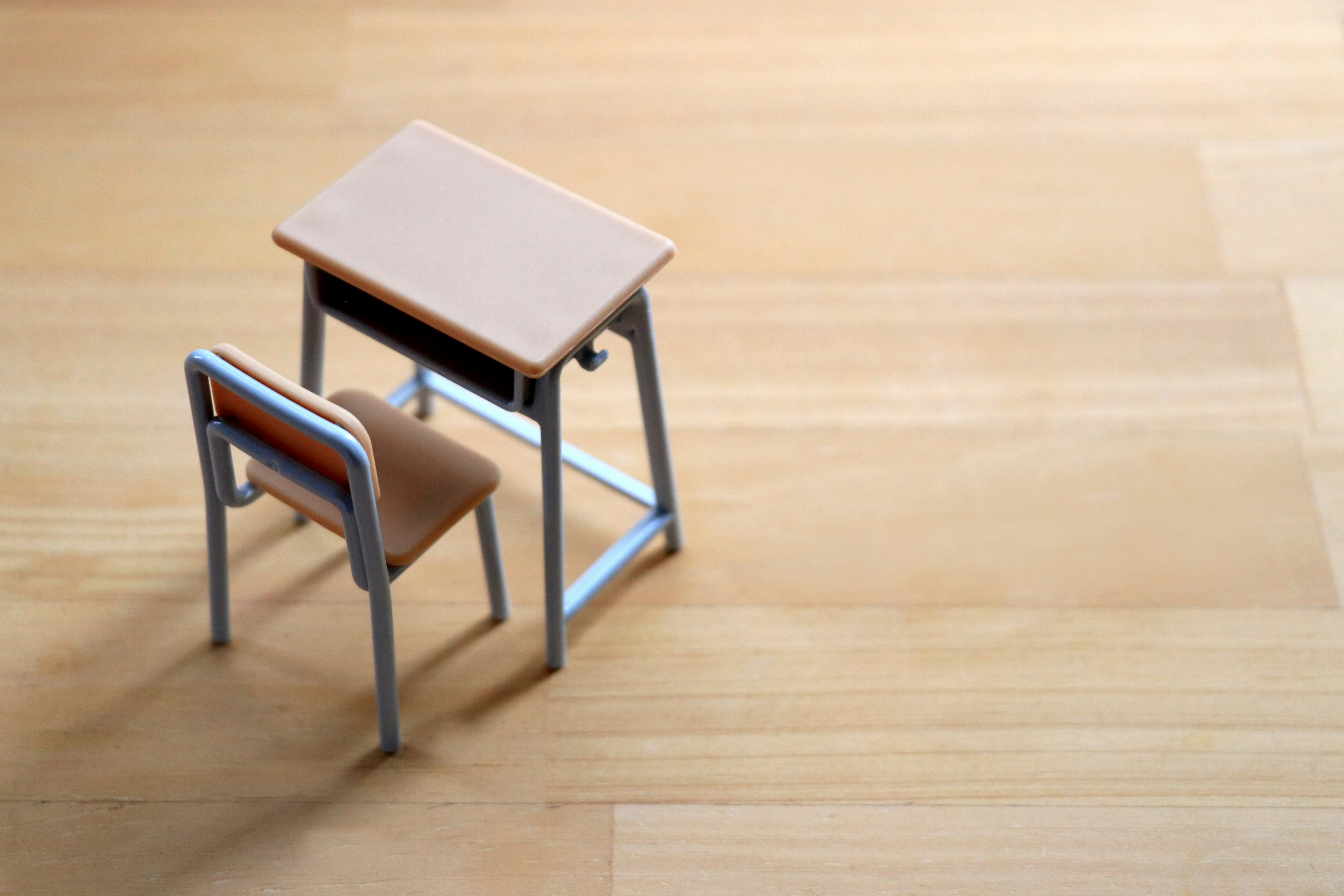 Un petit modèle de bureau et de chaise placé sur un sol en bois