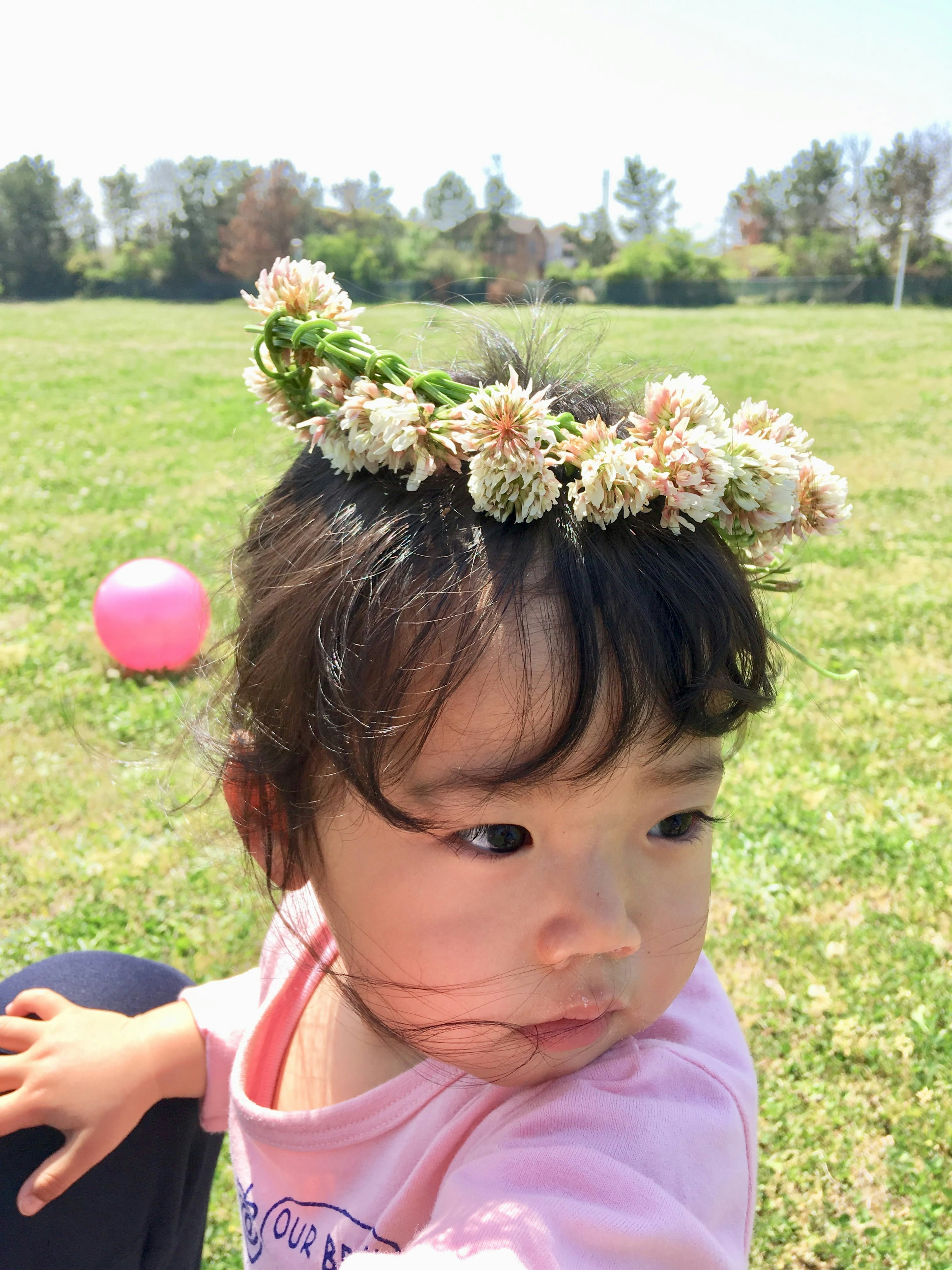 Mädchen mit einer Blumenkrone, das in einem Park spielt