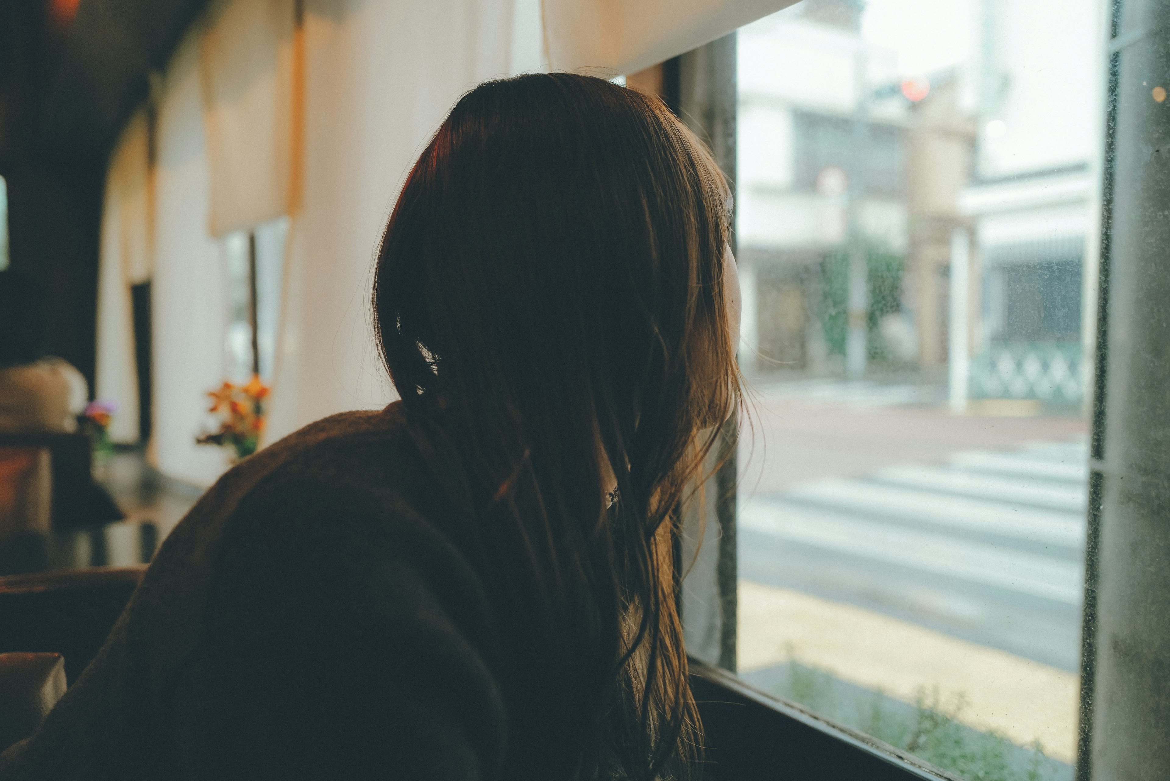 Donna che guarda fuori dalla finestra in un caffè illuminazione soffusa e atmosfera serena