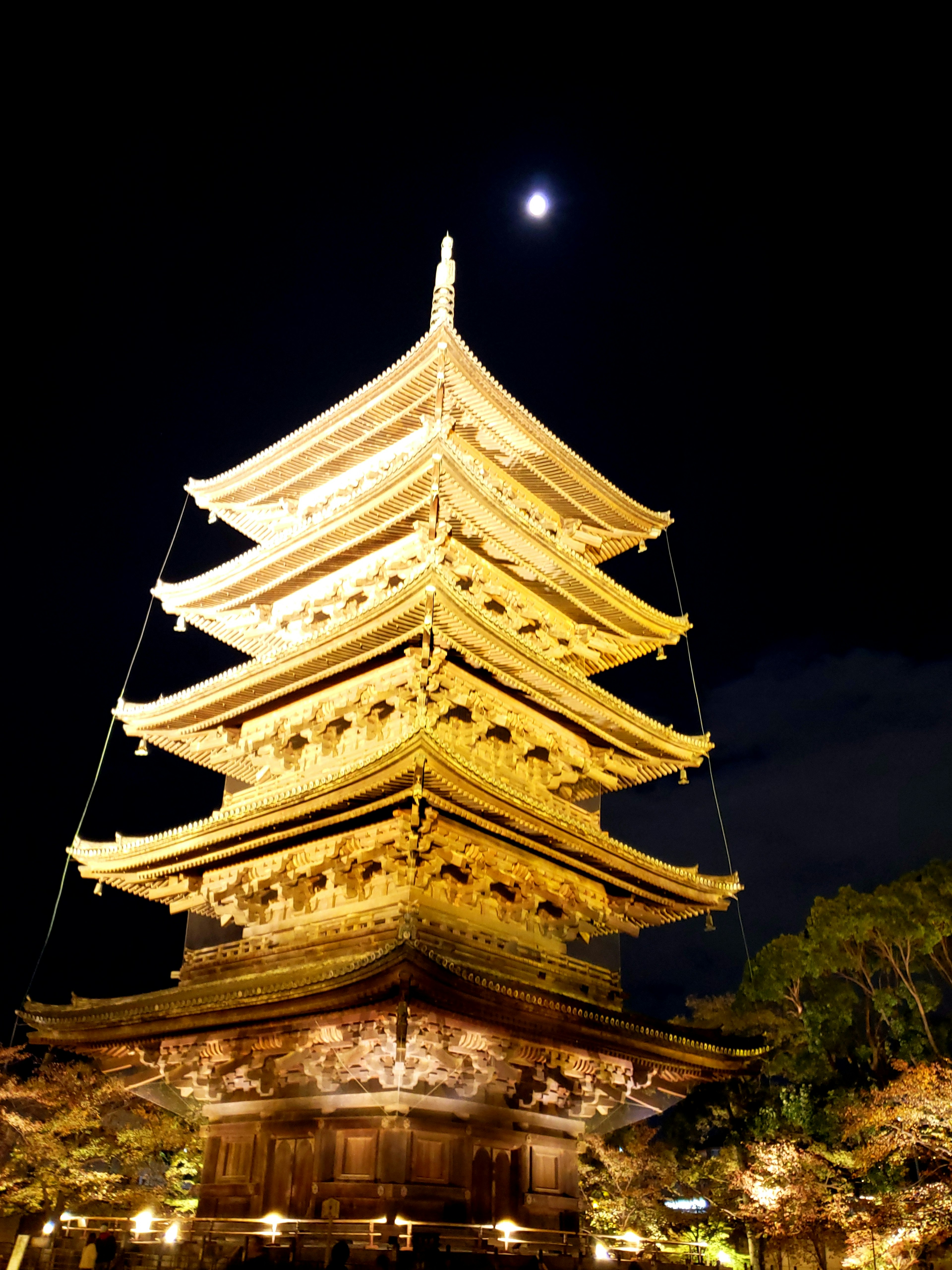 Five-story pagoda illuminated at night with a crescent moon