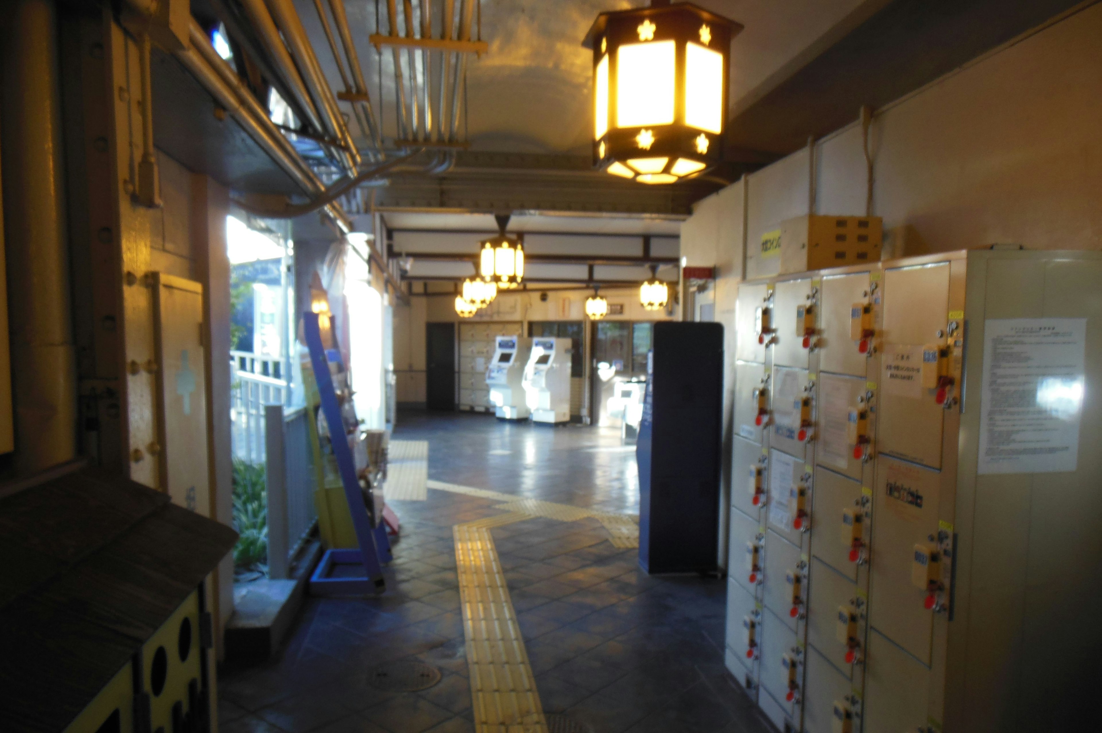 A corridor featuring lockers and hanging lights