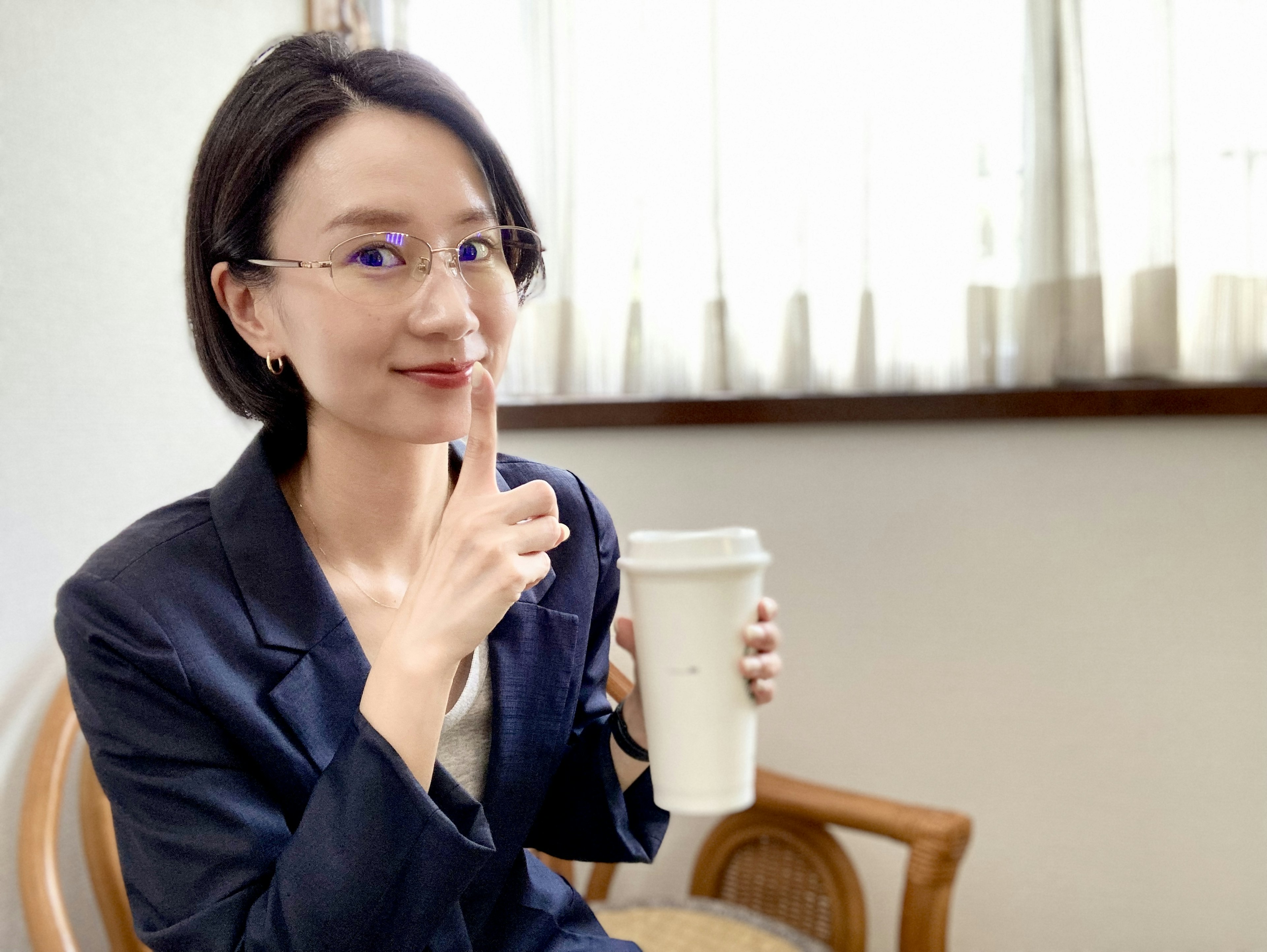 女性手持咖啡杯，安静地将手指放在嘴唇上