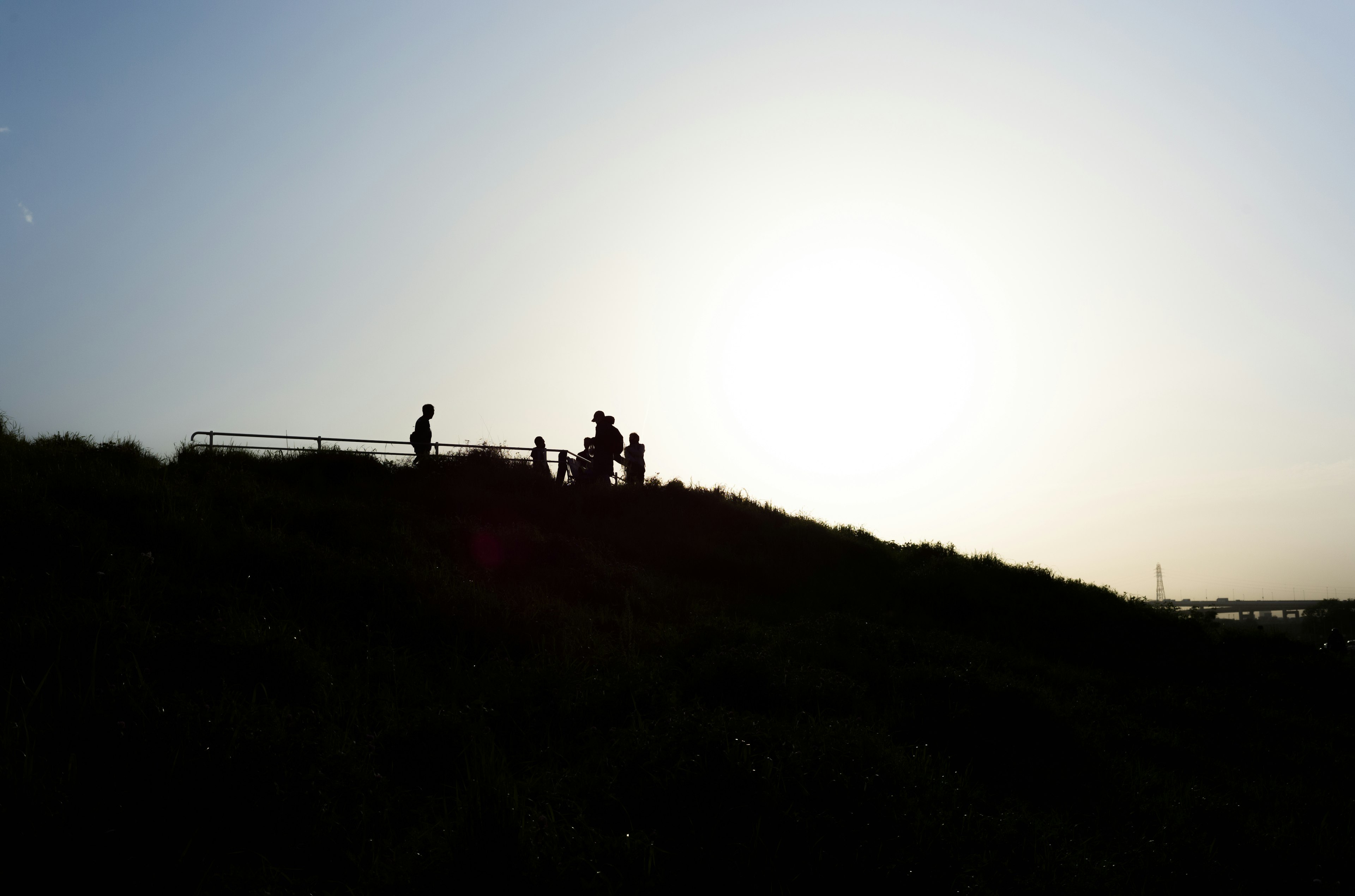 夕日を背景にシルエットの人々が丘の上に立っている風景