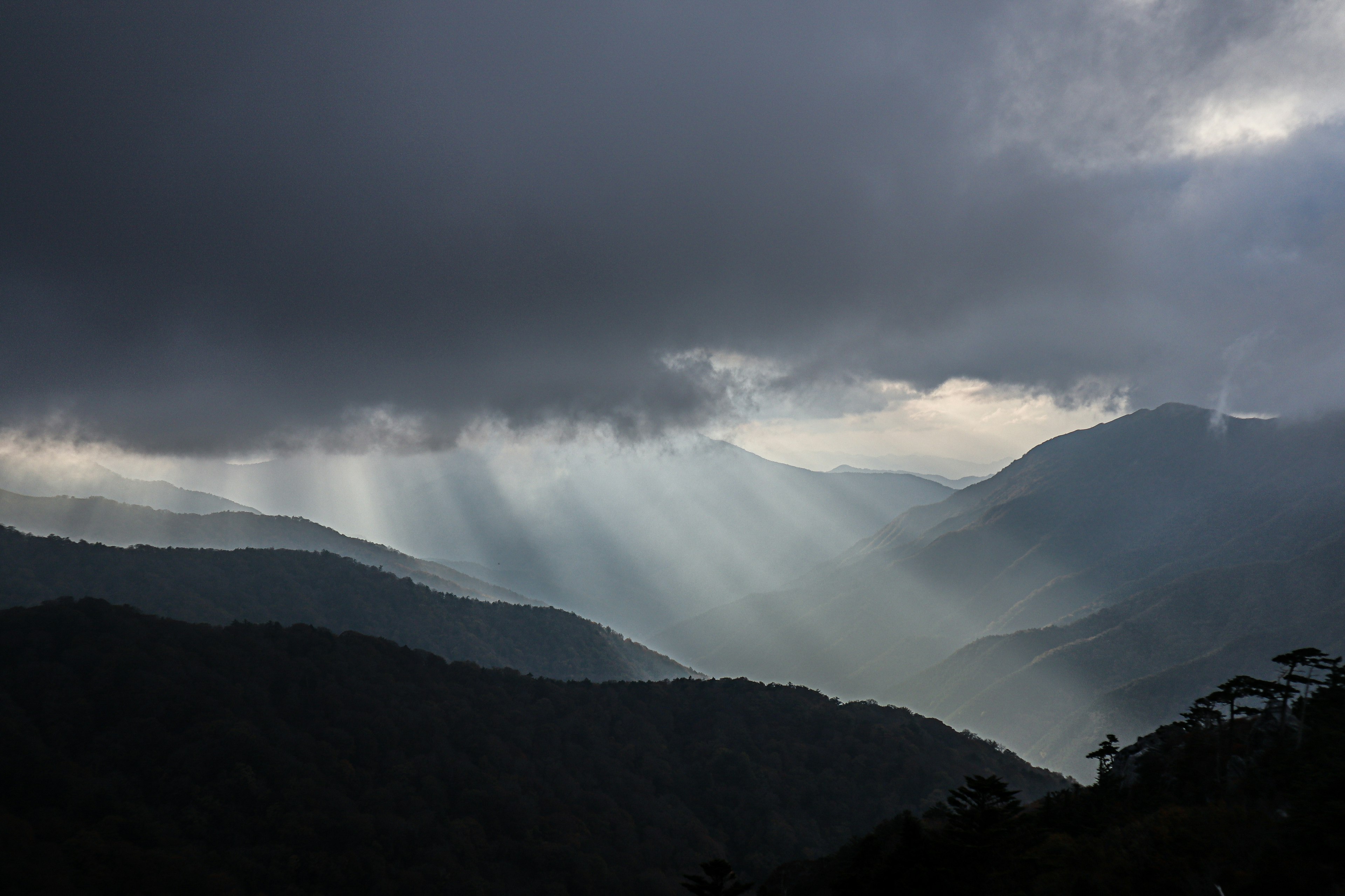 Beams of light breaking through clouds over mountains