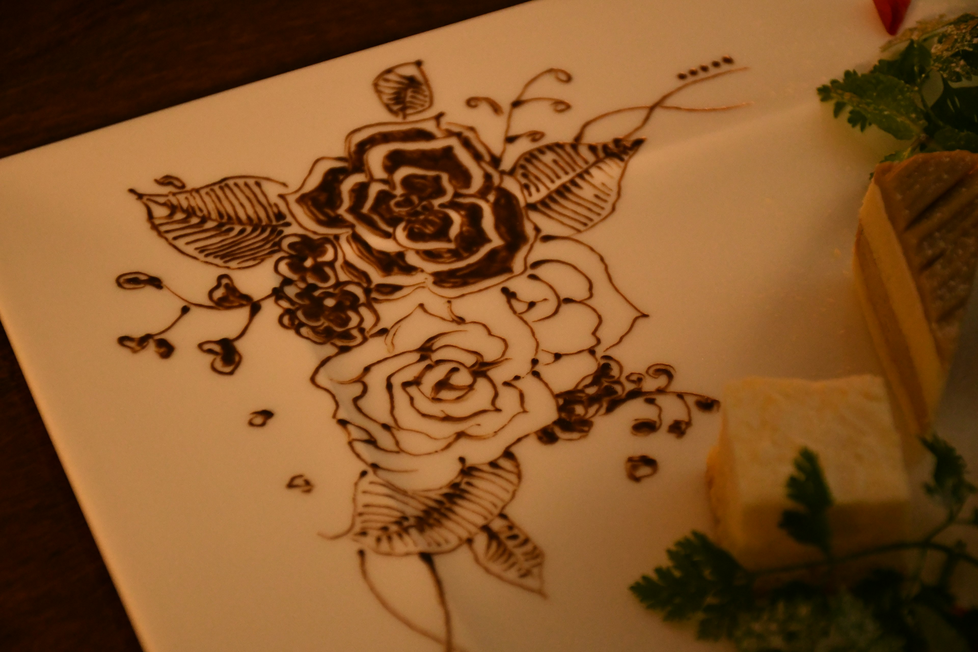 Une assiette blanche avec un design floral en encre noire comprenant des roses et des feuilles