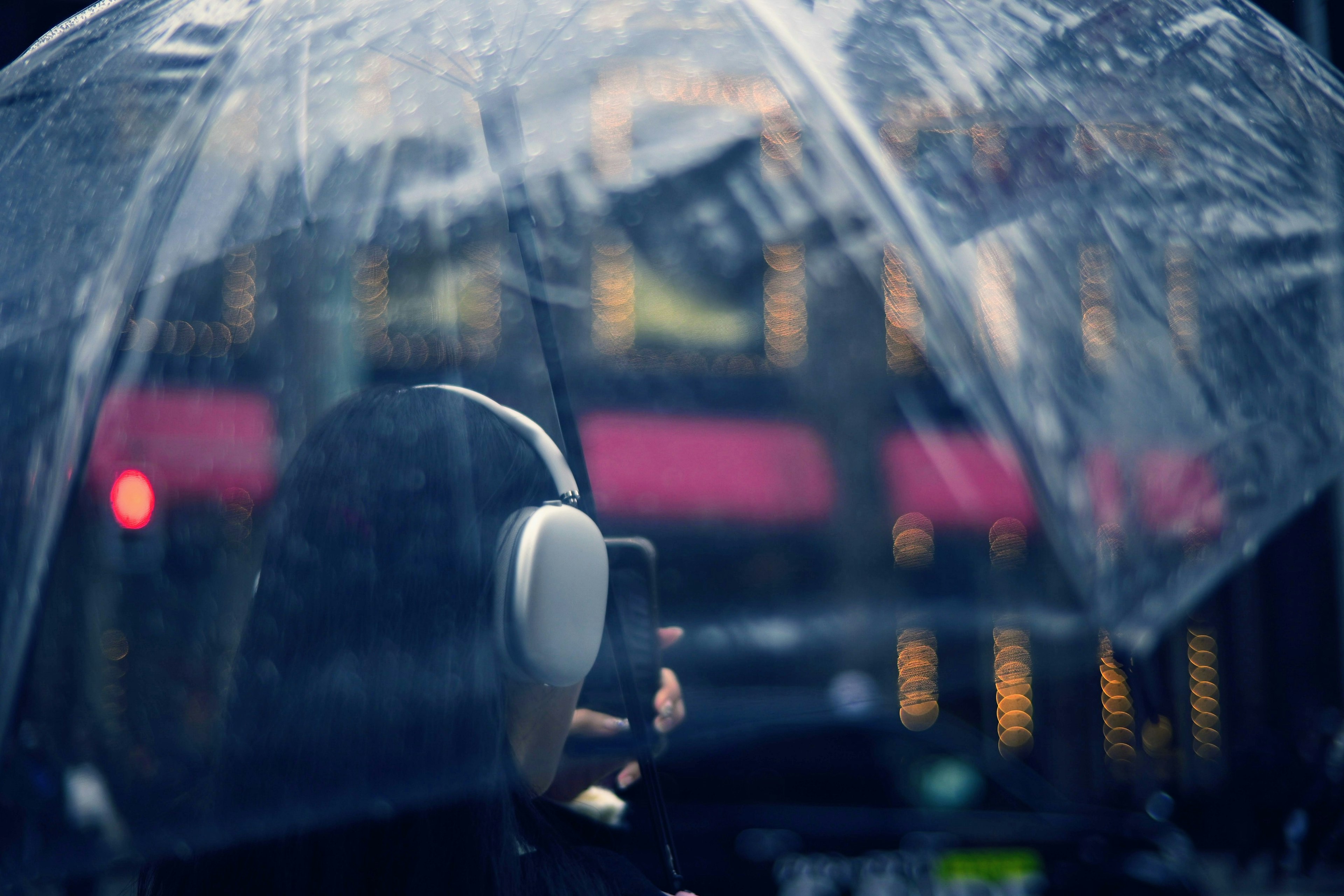 Silhouette einer Person, die einen Regenschirm hält und im Regen Musik hört