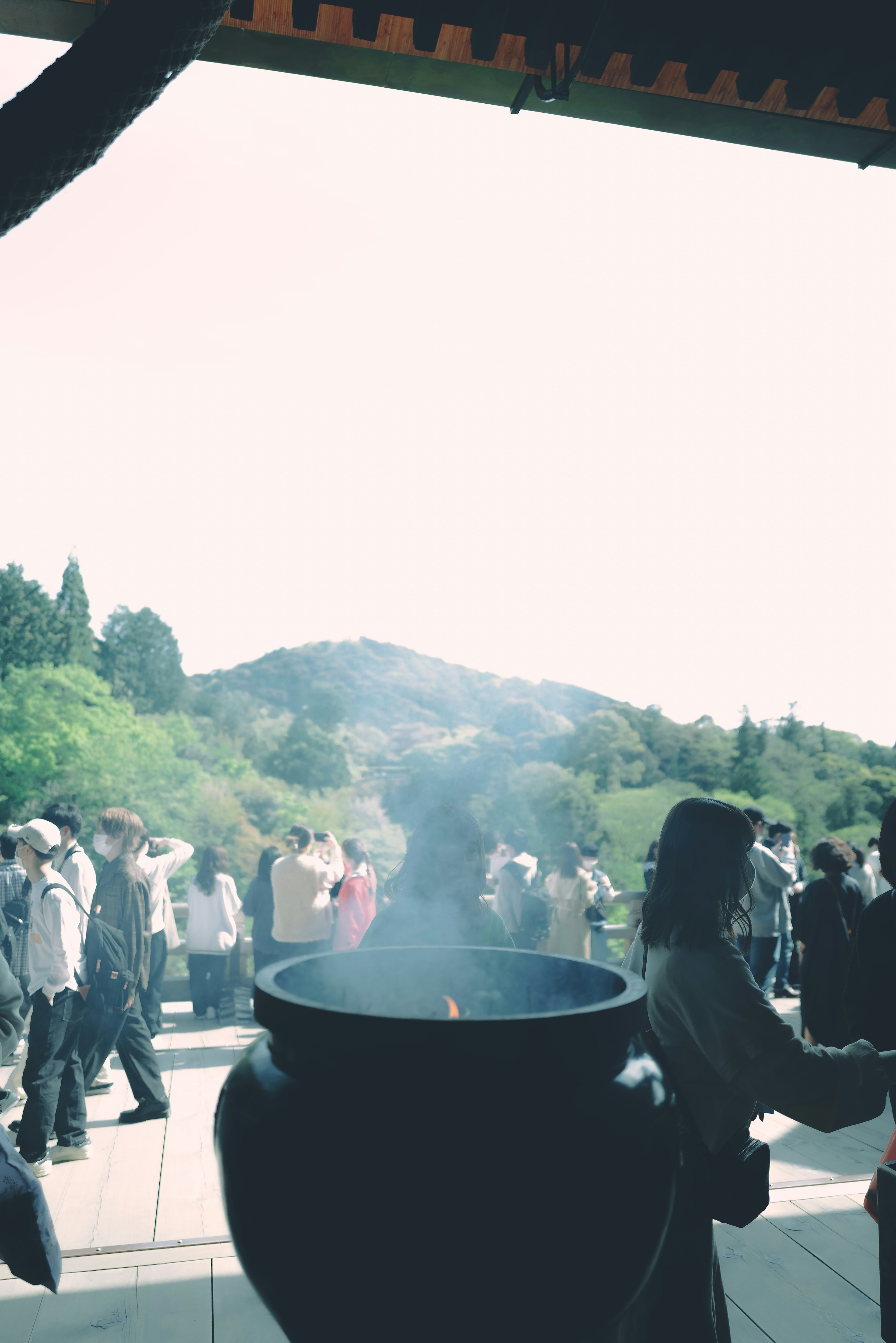 煙が立ち上る大きな香炉と背景の山々を眺める人々