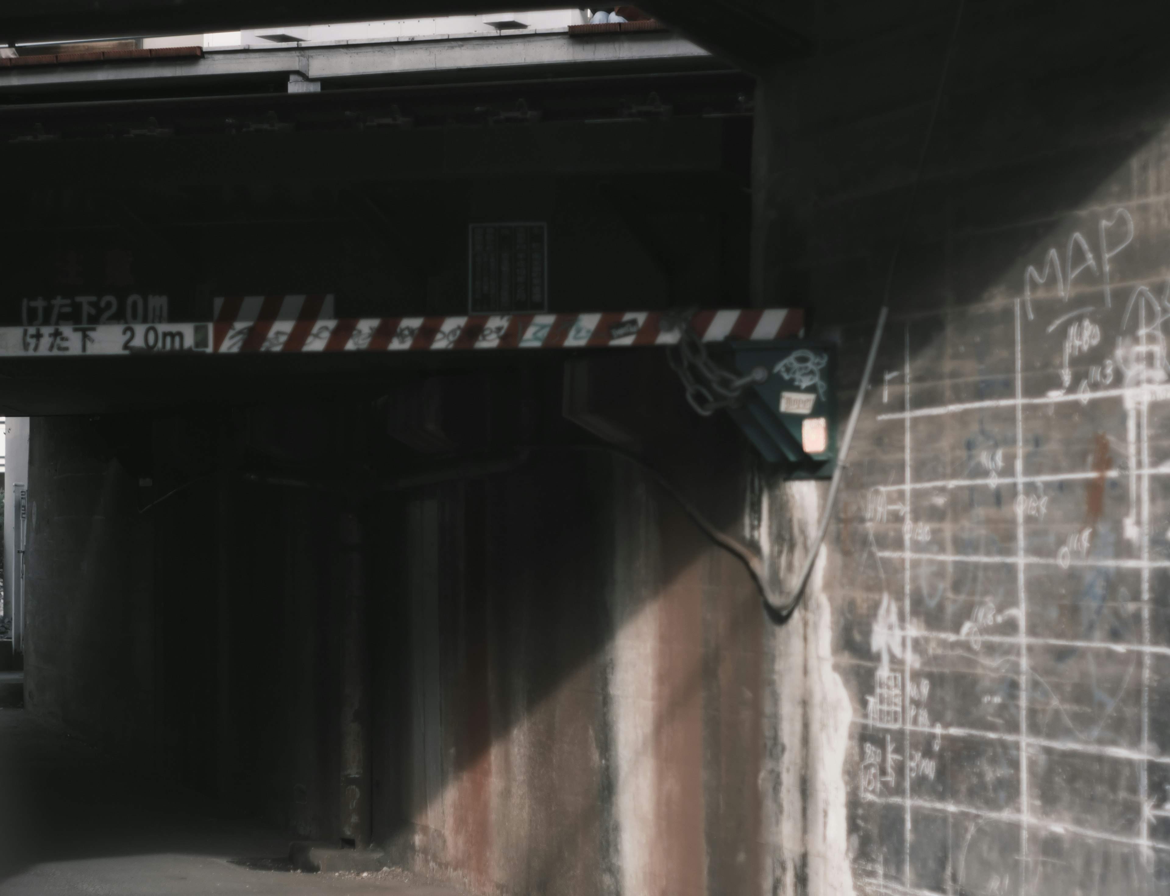 Entrance to a dark tunnel with a red and white barrier and graffiti on the wall