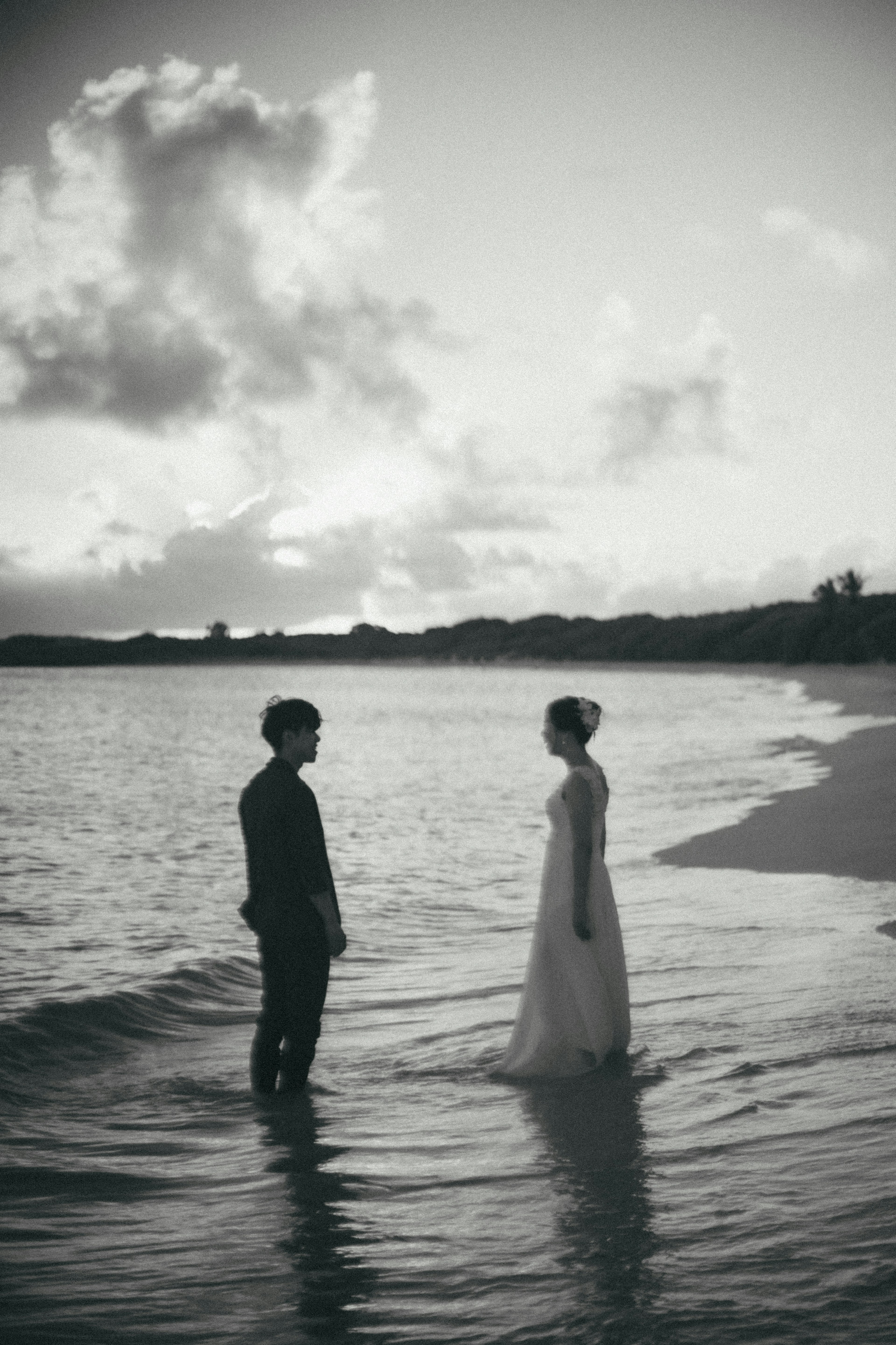 Black and white photo of a couple facing each other by the seaside