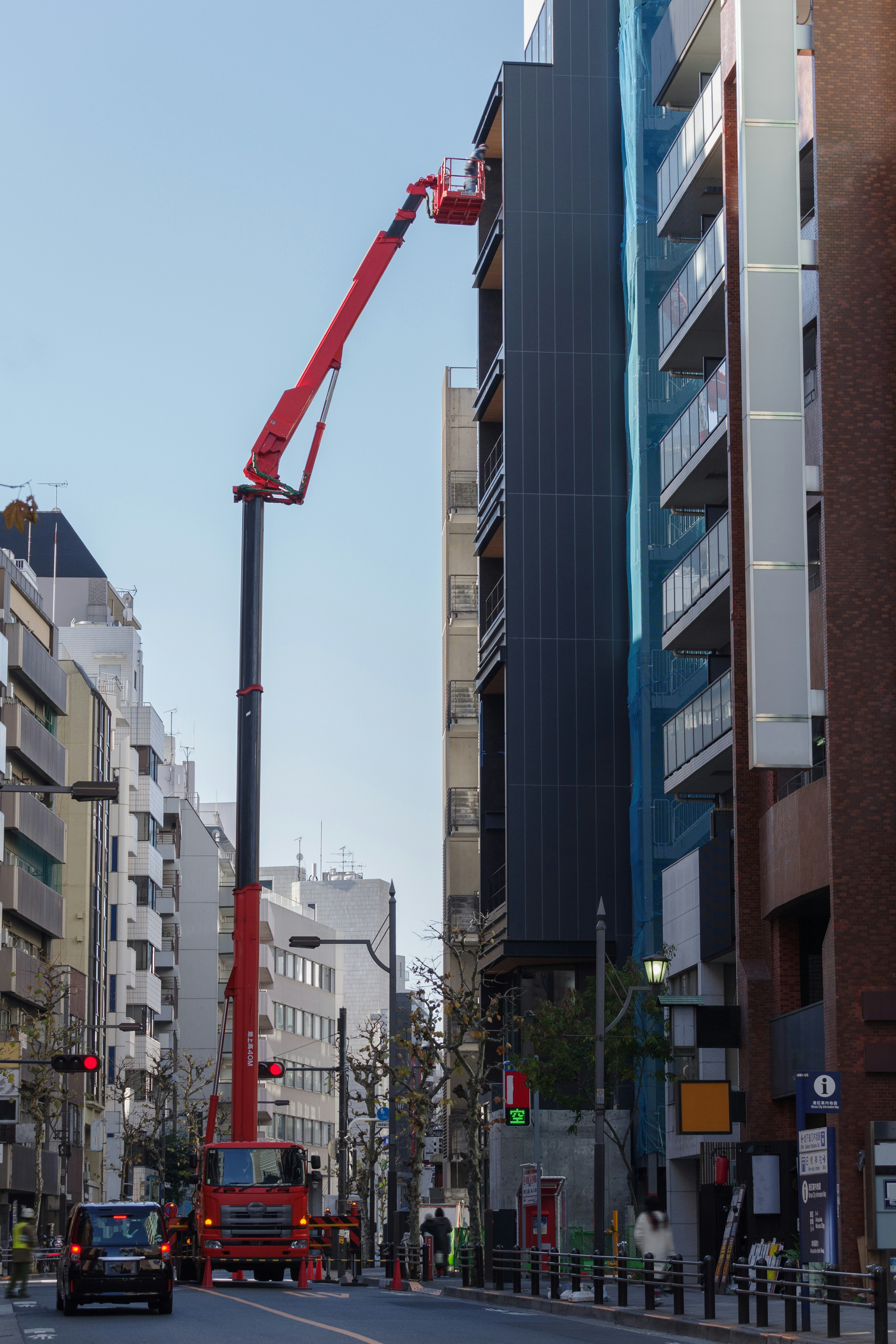 Grúa roja trabajando en el lado de un edificio de gran altura en un entorno urbano