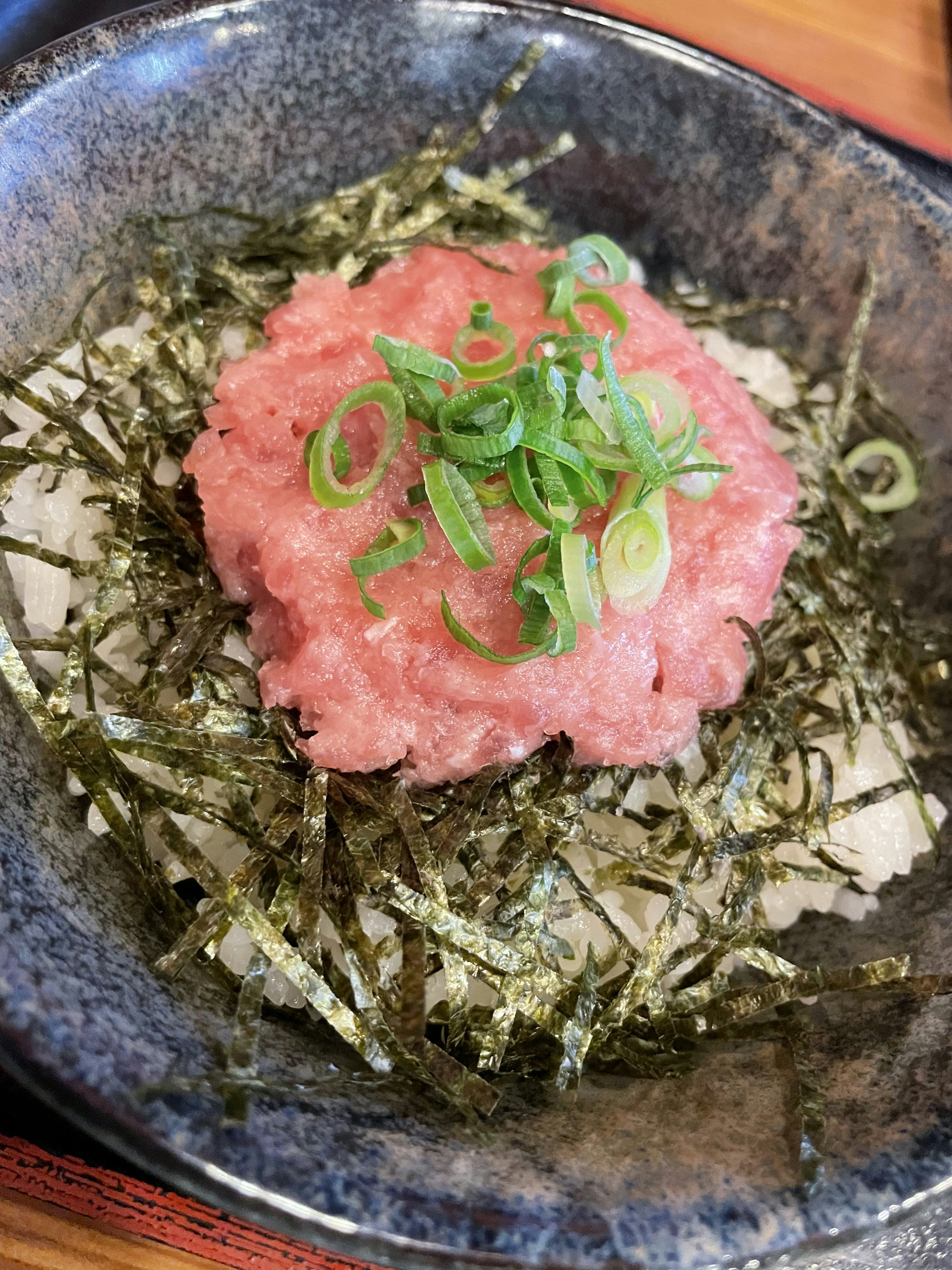 海苔の上にネギがトッピングされた生魚の丼