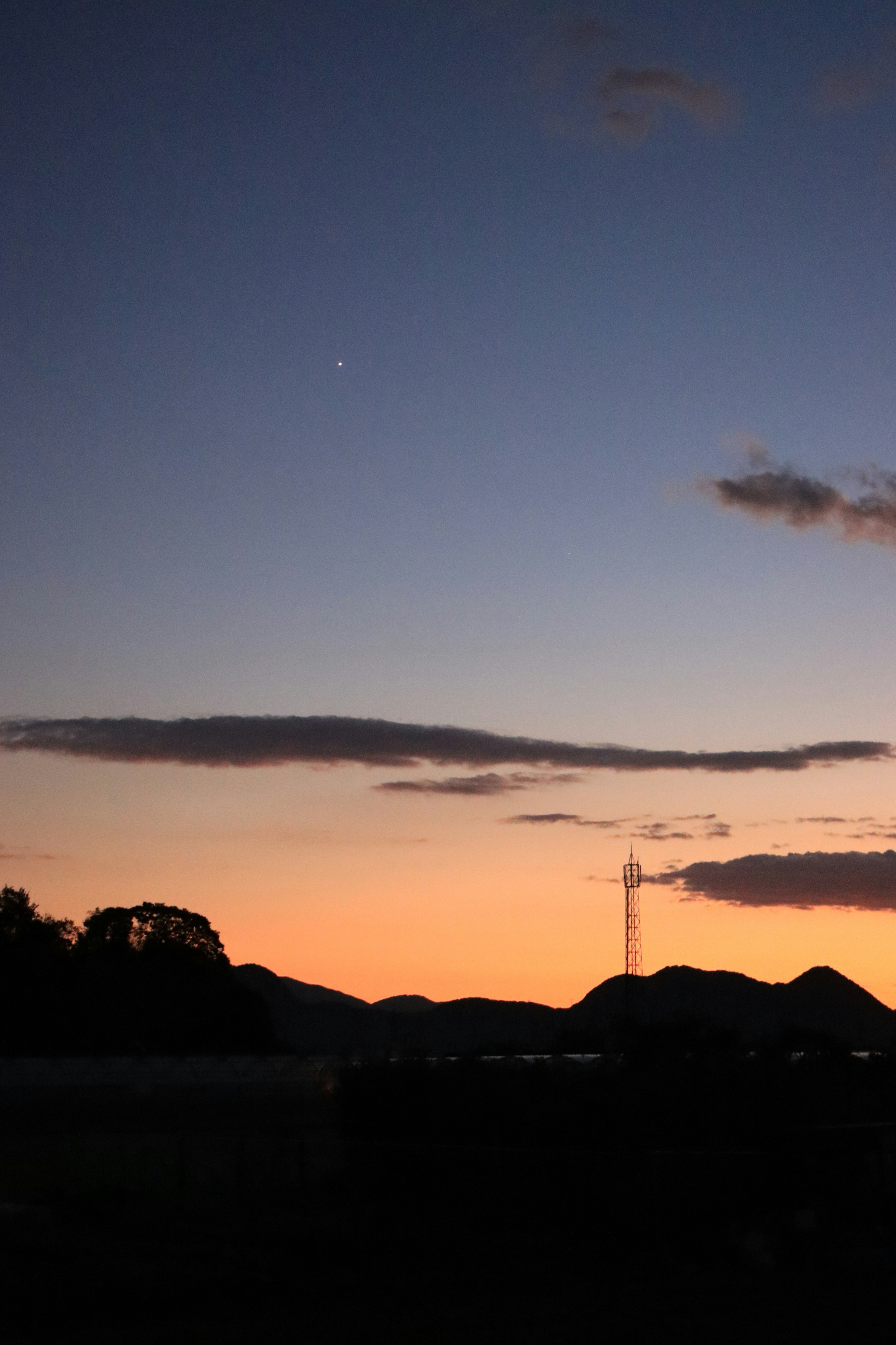 Siluet pegunungan di bawah langit senja dengan awan